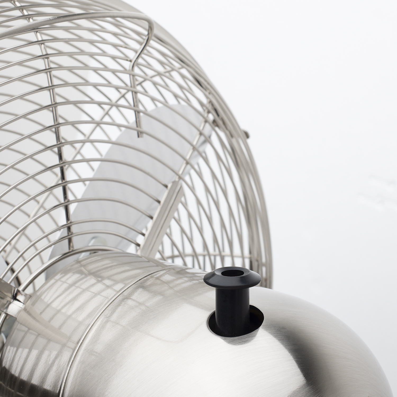 Un primo piano di un ventilatore argentato, con le pale visibili, su sfondo bianco.