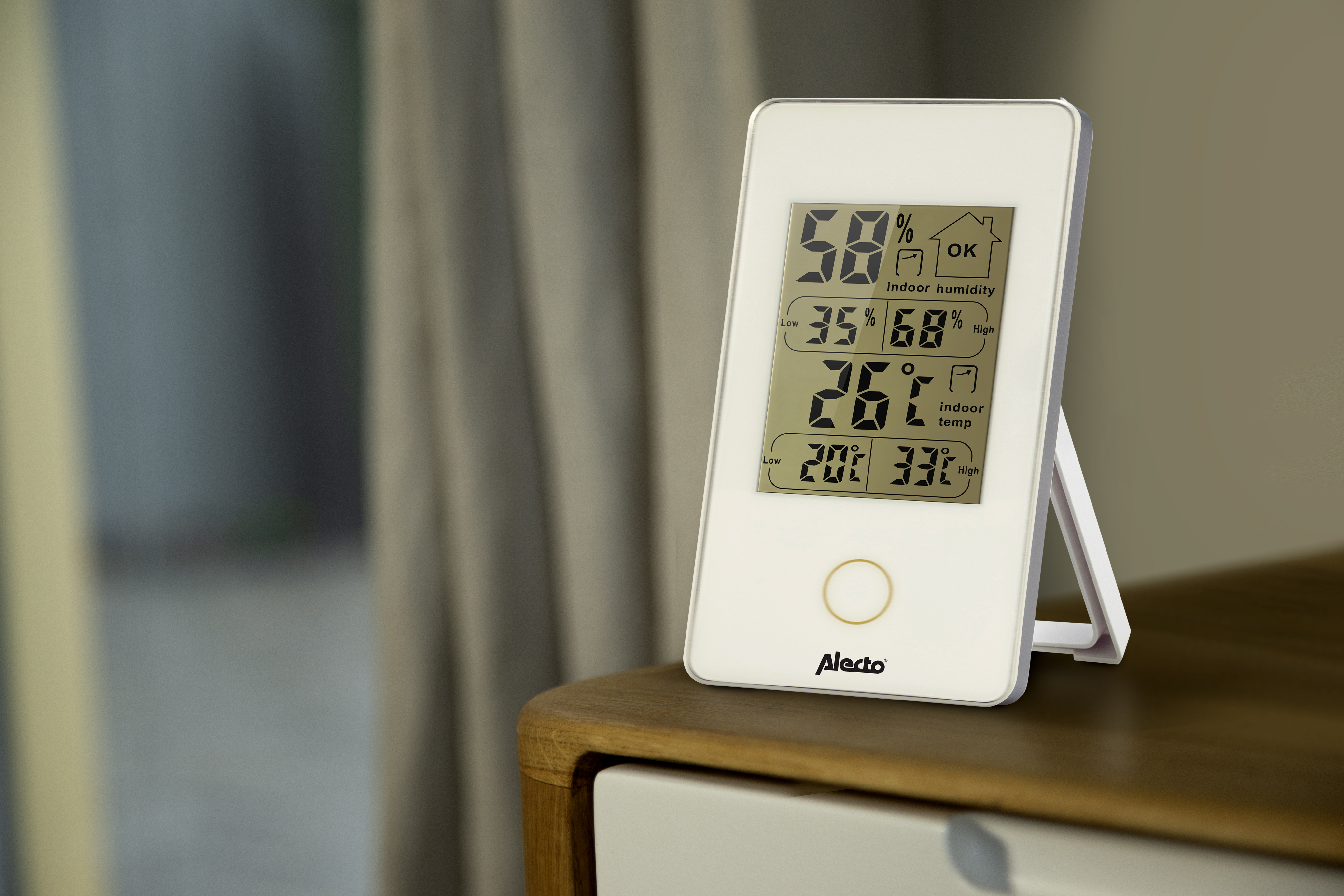 Display digitale bianco che mostra umidità e temperatura interna. Su un tavolo di legno.