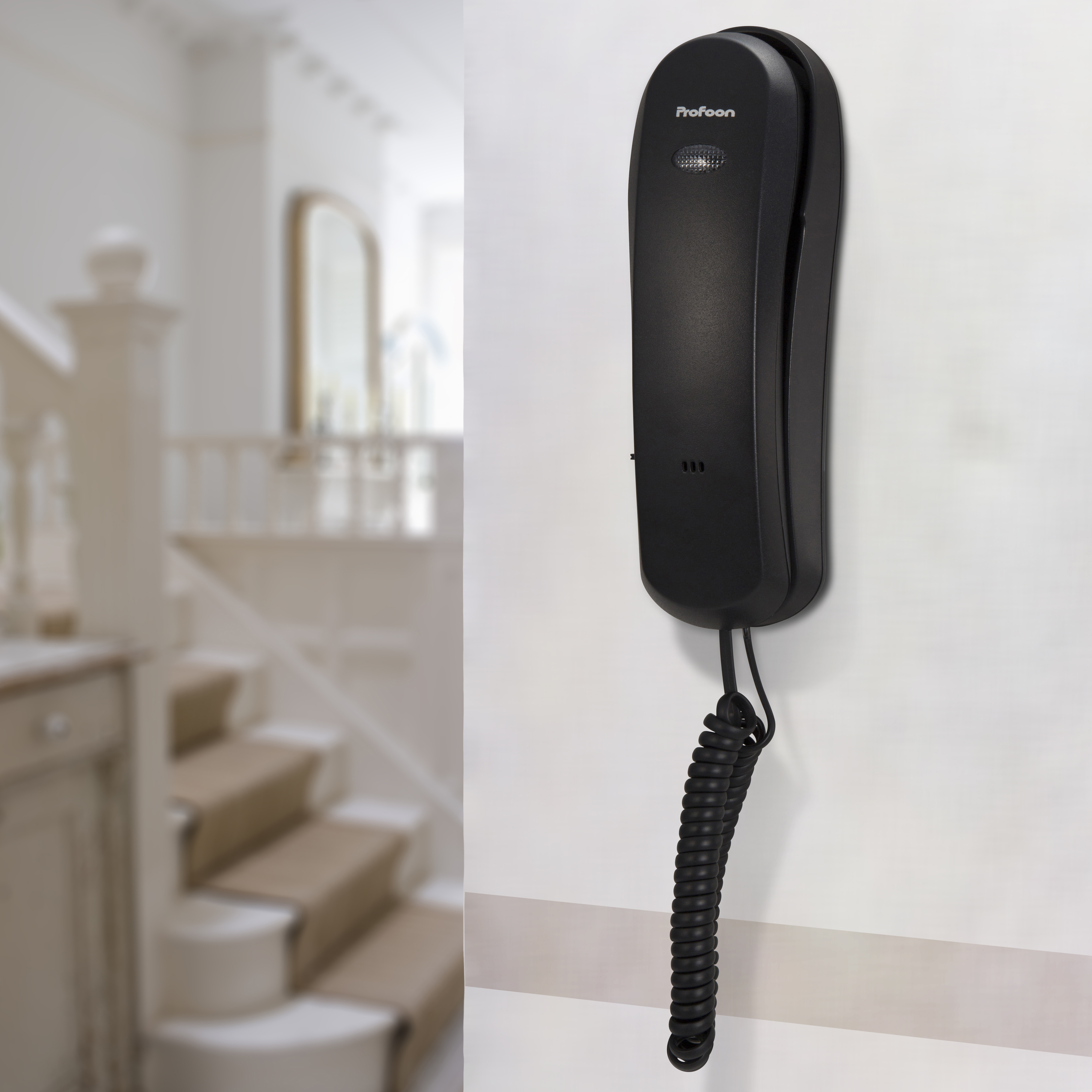 Ein schwarzes Wandtelefon mit einer Spiralschnur, die vor einer verschwommenen Innenszene herunterhängt.
