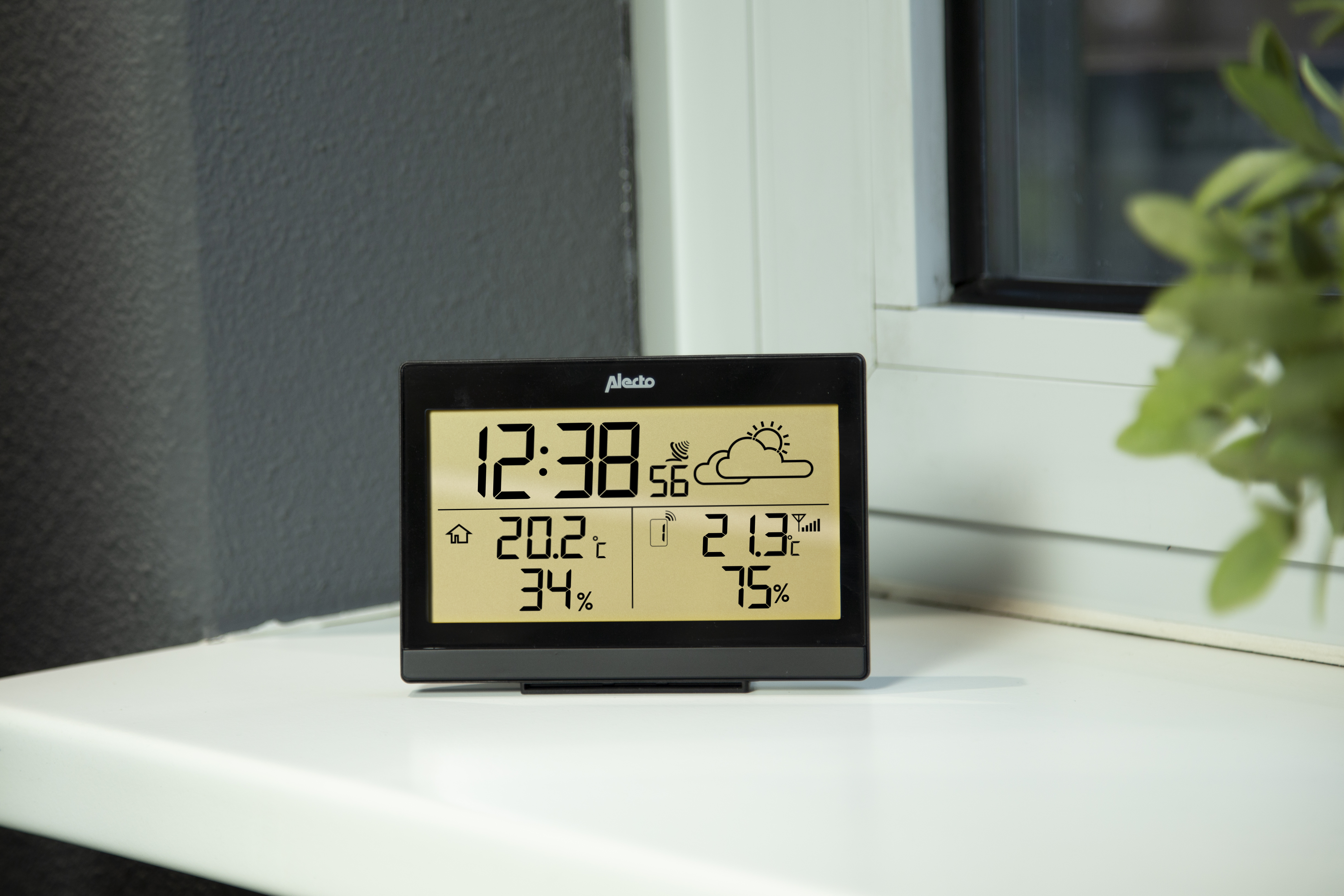 Stazione meteorologica digitale nera su una superficie bianca. Mostra ora, temperatura, umidità e simboli meteo.