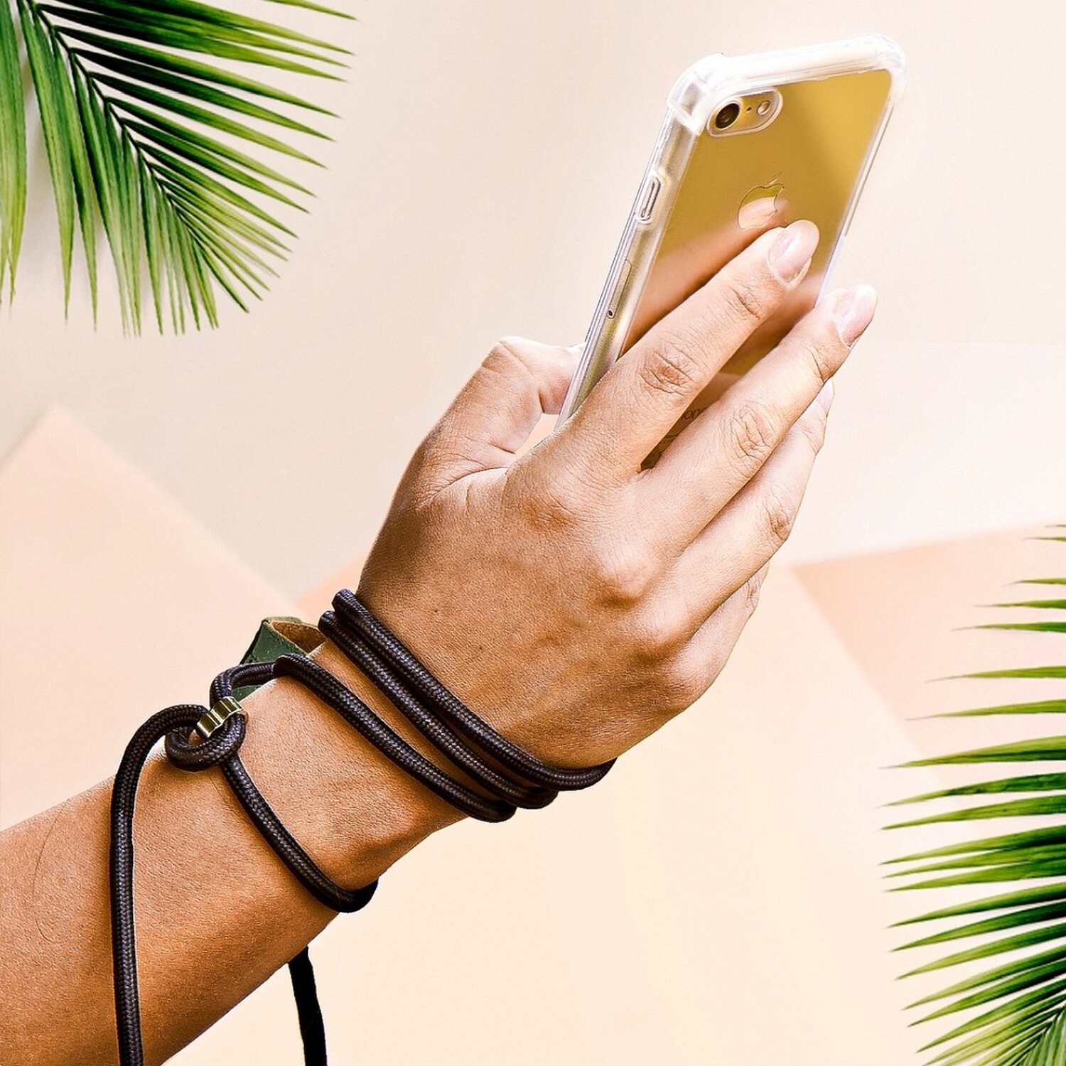 Eine Hand, die ein Telefon mit einem Handgelenkriemen hält, vor einem verschwommenen Hintergrund.