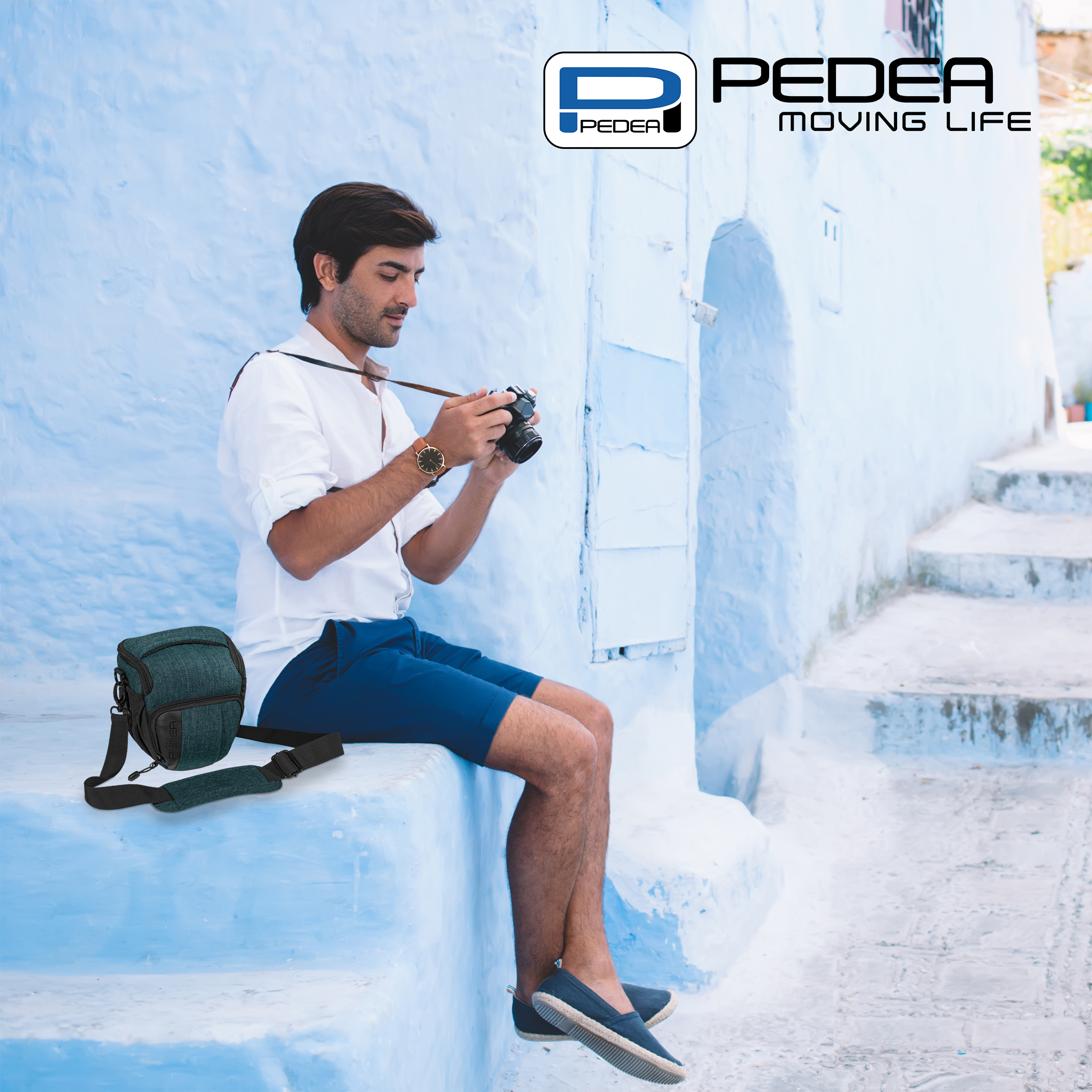 Mann, der ein Foto mit einer Kamera macht, trägt ein weißes Hemd und blaue Shorts, mit einer Tasche.