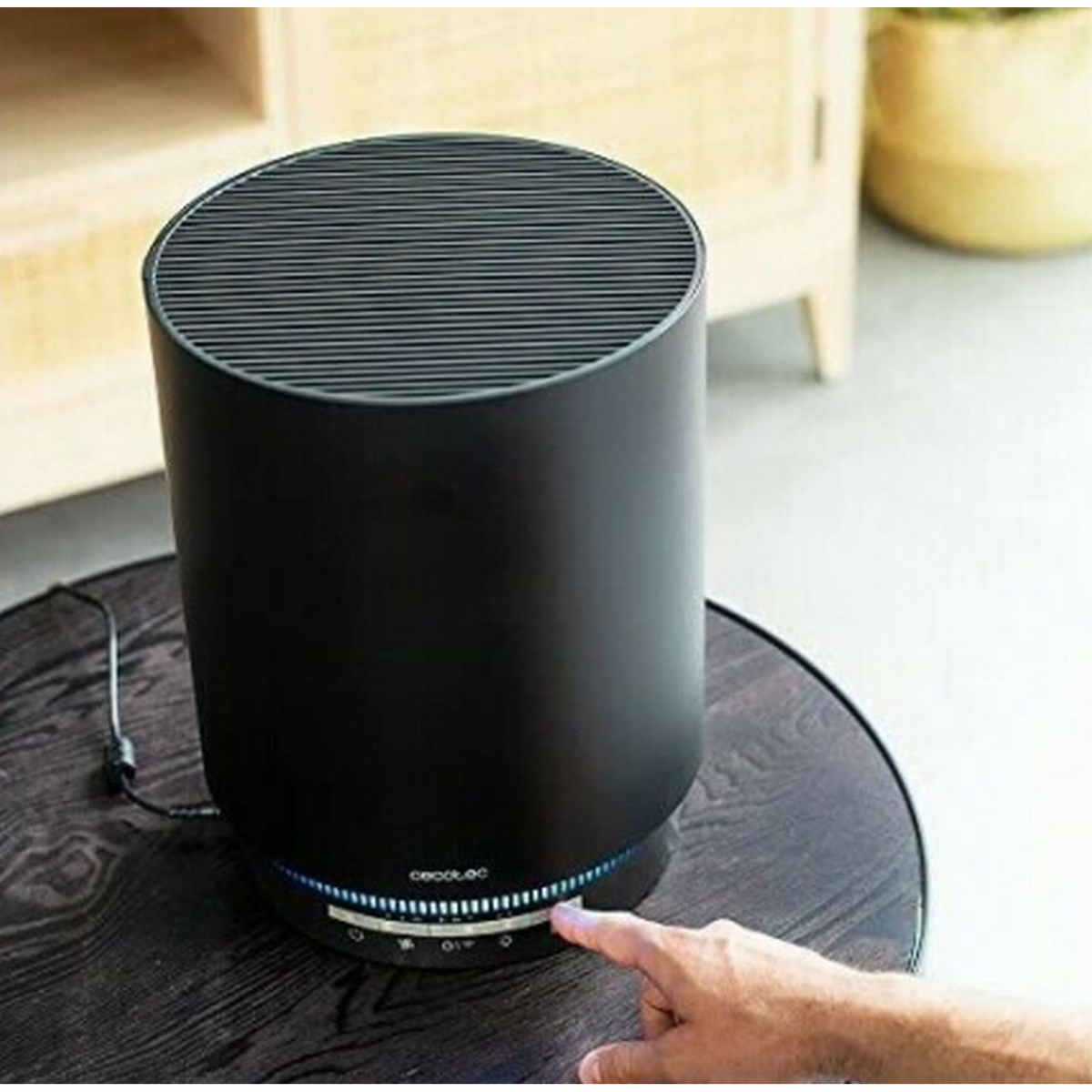 Purificatore d'aria nero con corpo rotondo e griglia superiore, su tavolo di legno.