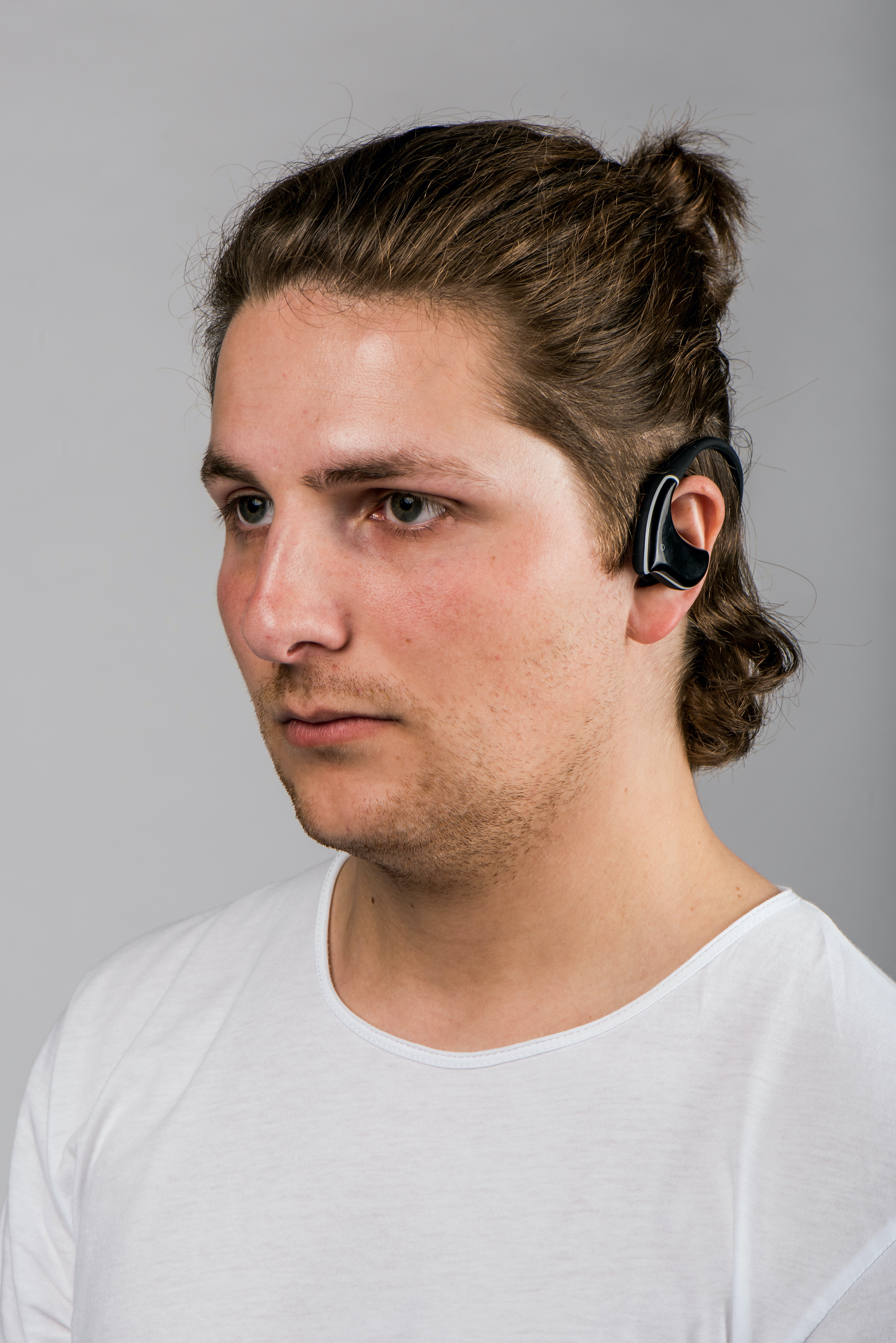 Uomo con capelli castani raccolti con cuffia nera. Sfondo grigio chiaro.