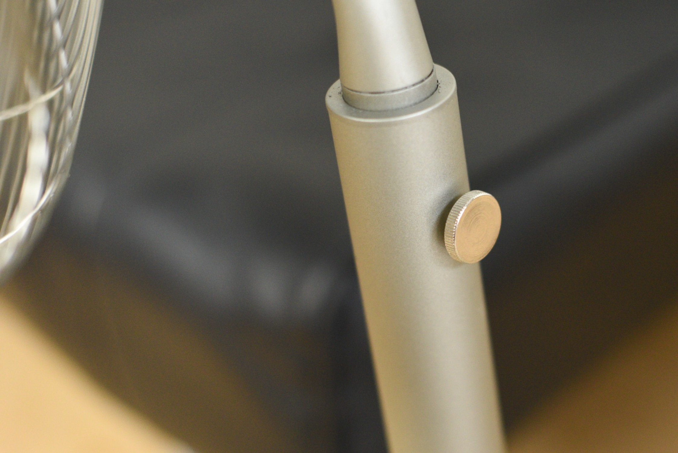 Close-up of a fan's stand. Silver, round base with a button.