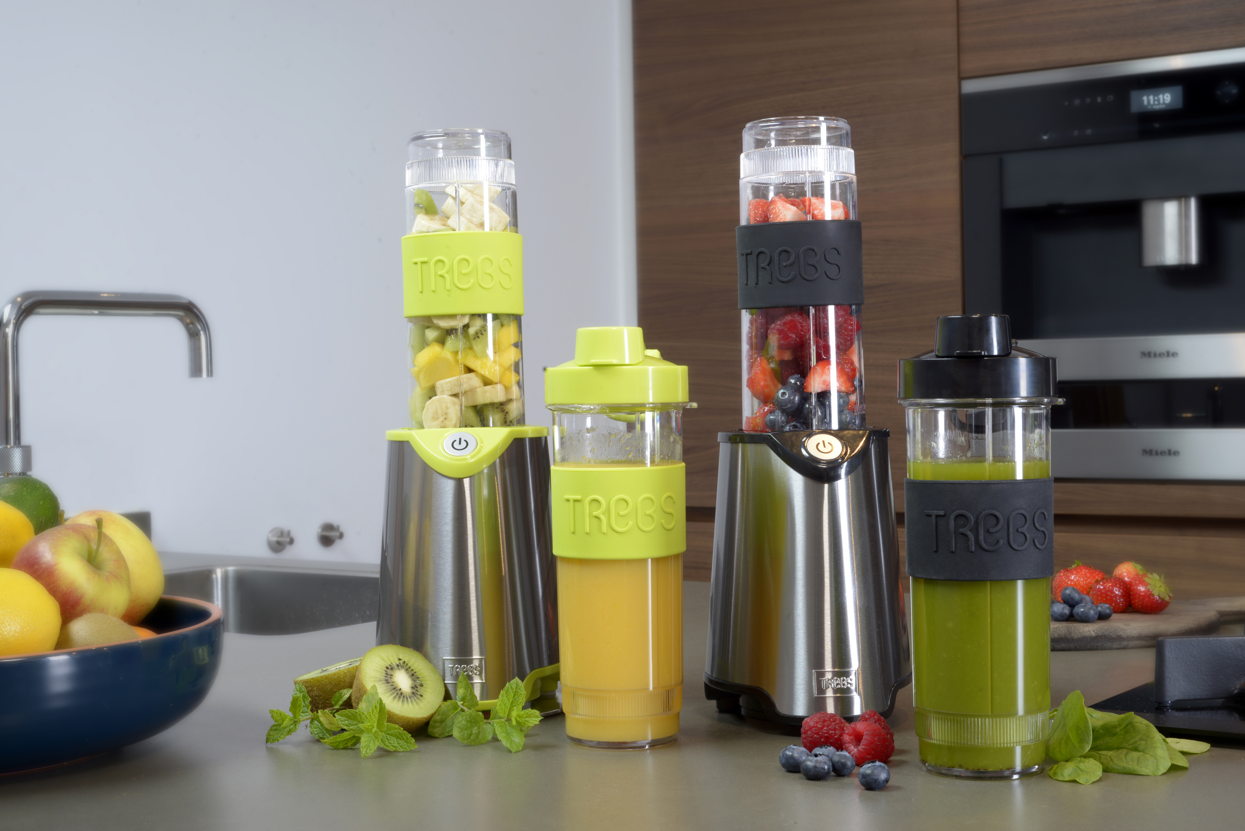 Set frullatore con quattro diversi contenitori con frutta e verdura all'interno. Sfondo cucina.