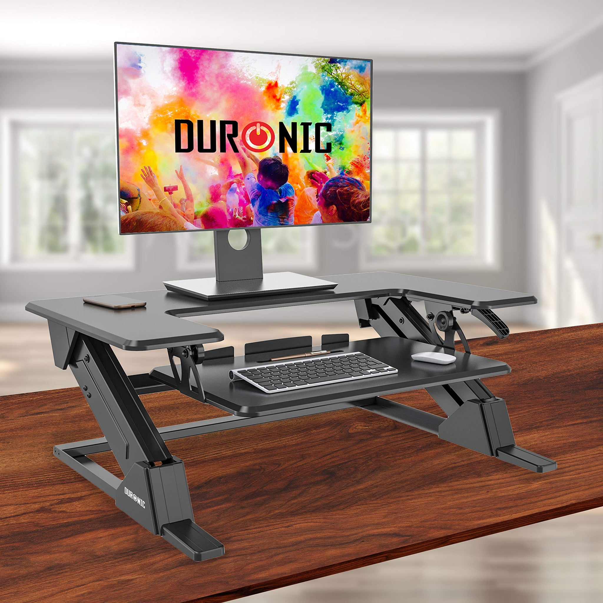 Ein schwarzer Stehtisch mit Monitor, Tastatur und Maus auf Holz. DURNIC Logo sichtbar.