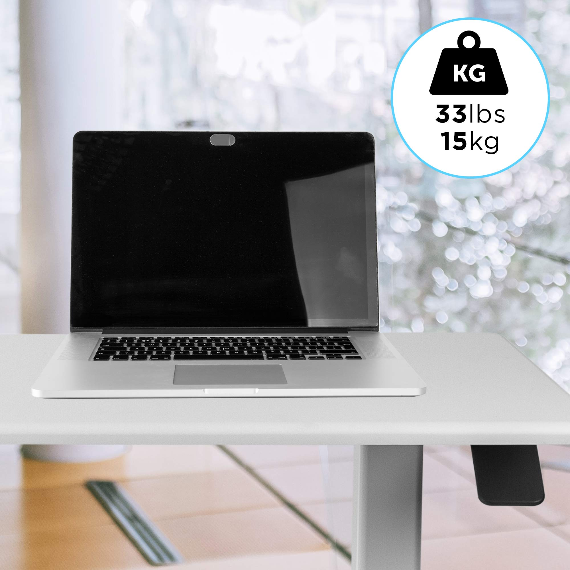 Laptop en un escritorio blanco. La tapa tiene una cubierta de webcam. Etiqueta muestra capacidad de 33lbs/15kg.