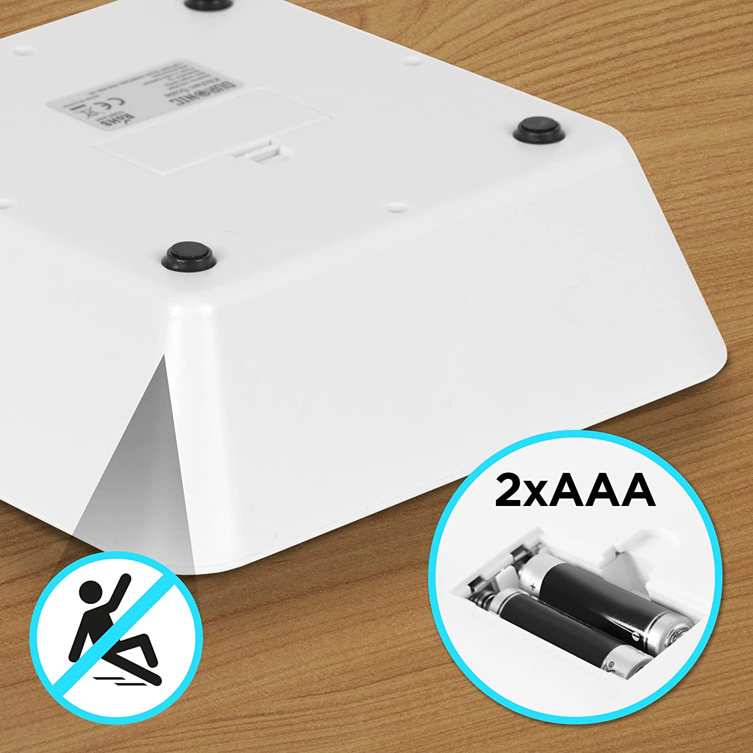 Weiße Gerätebasis mit offenem Batteriefach, zeigt 2 AAA-Batterien und ein Anti-Rutsch-Symbol.