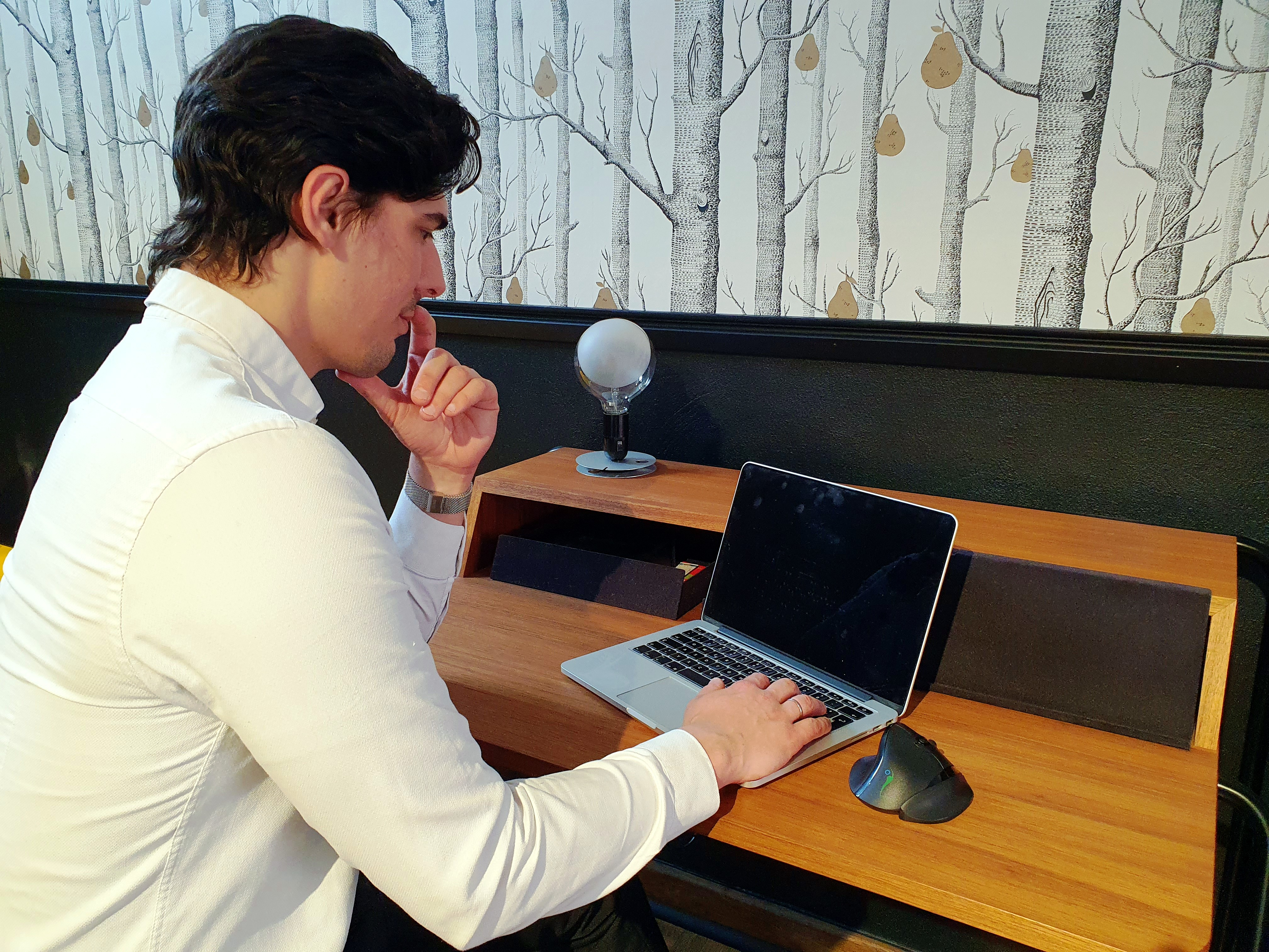 Mann benutzt Laptop an einem Holzschreibtisch mit Licht und Mikrofon.