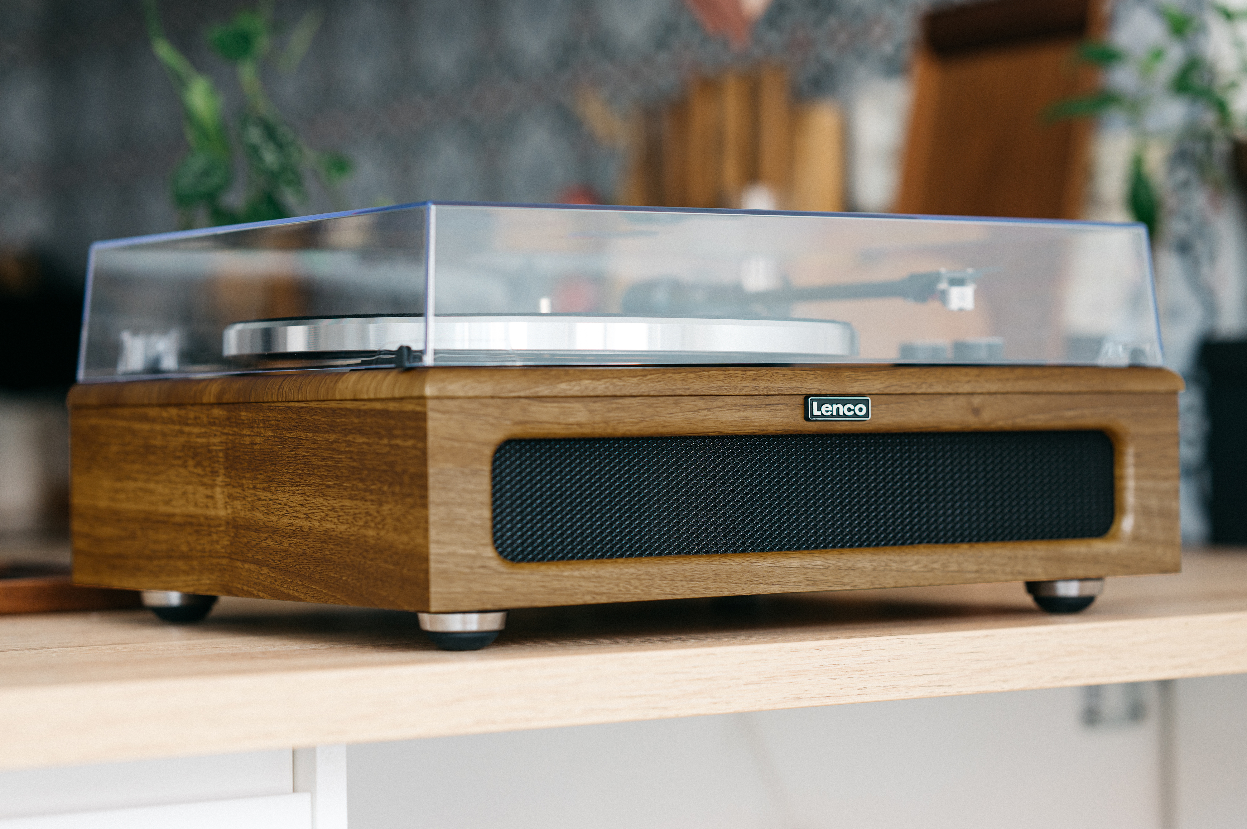 Tocadiscos de madera con cubierta transparente, sobre una estantería. Marca Lenco visible.