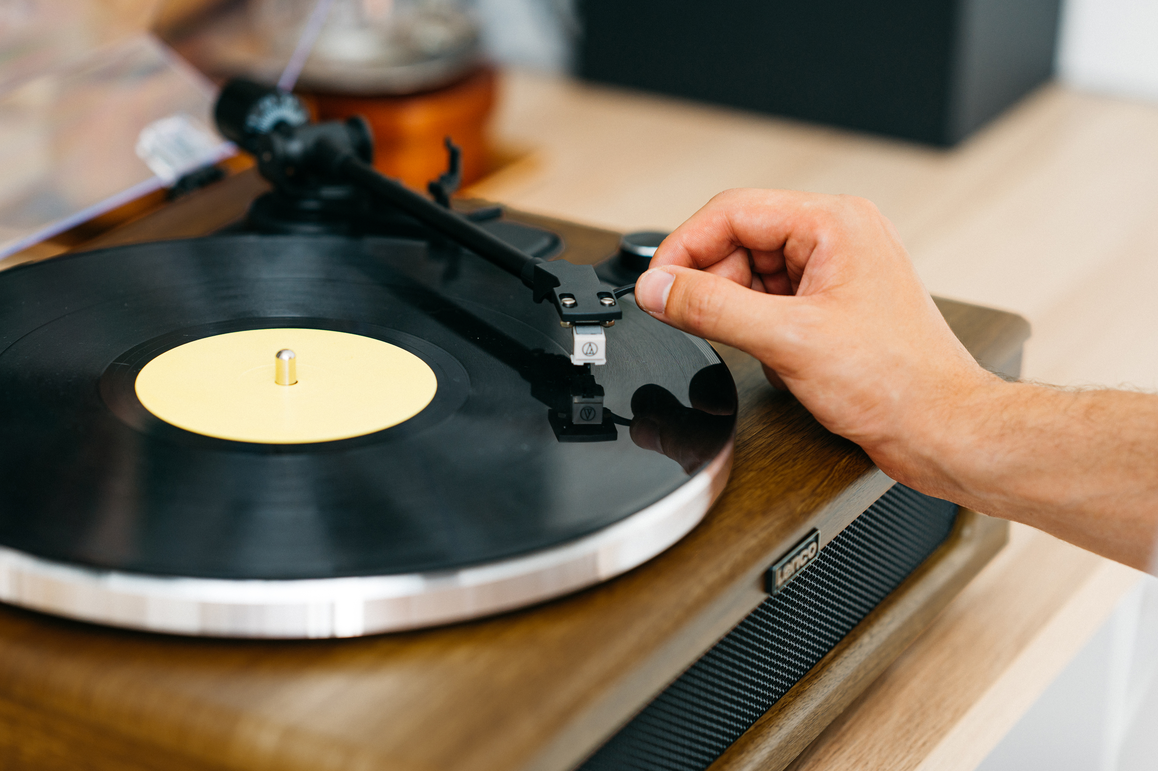 Mano ajustando la aguja de un tocadiscos en un disco de vinilo negro.