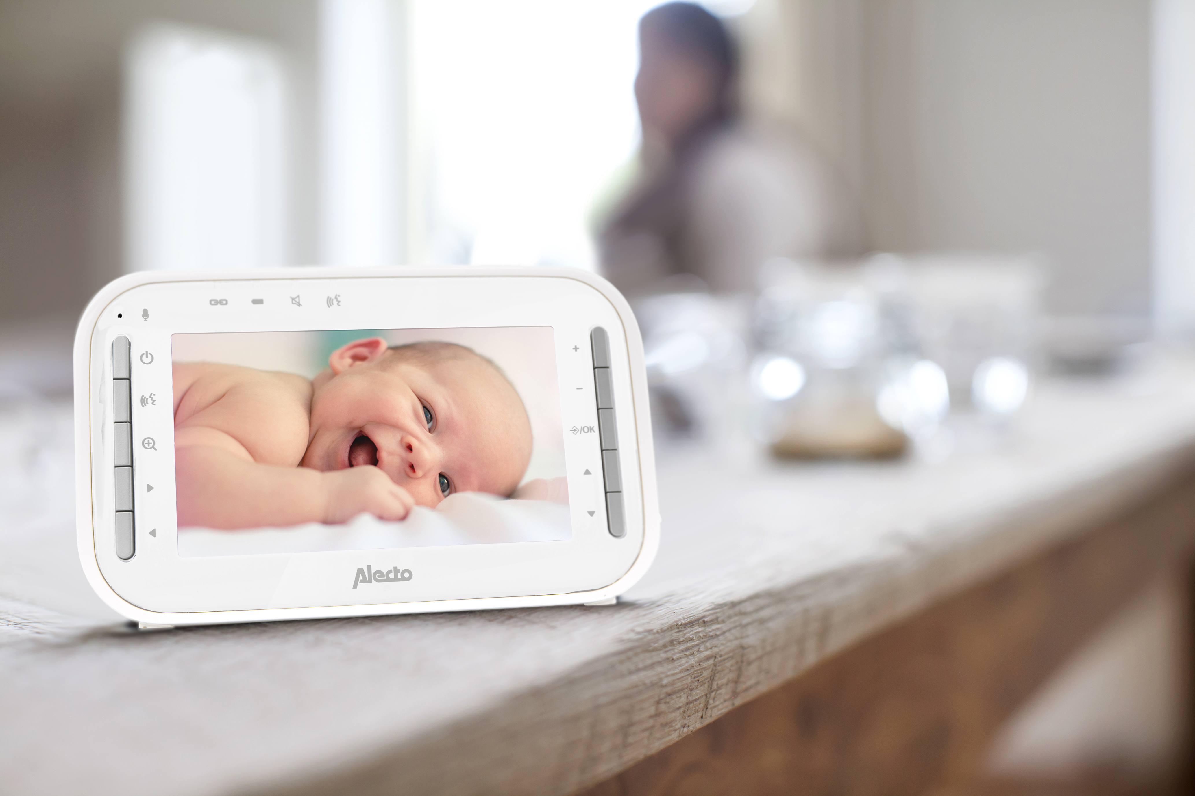 Babyphone zeigt lächelndes Baby in weiß-grauem Raum.