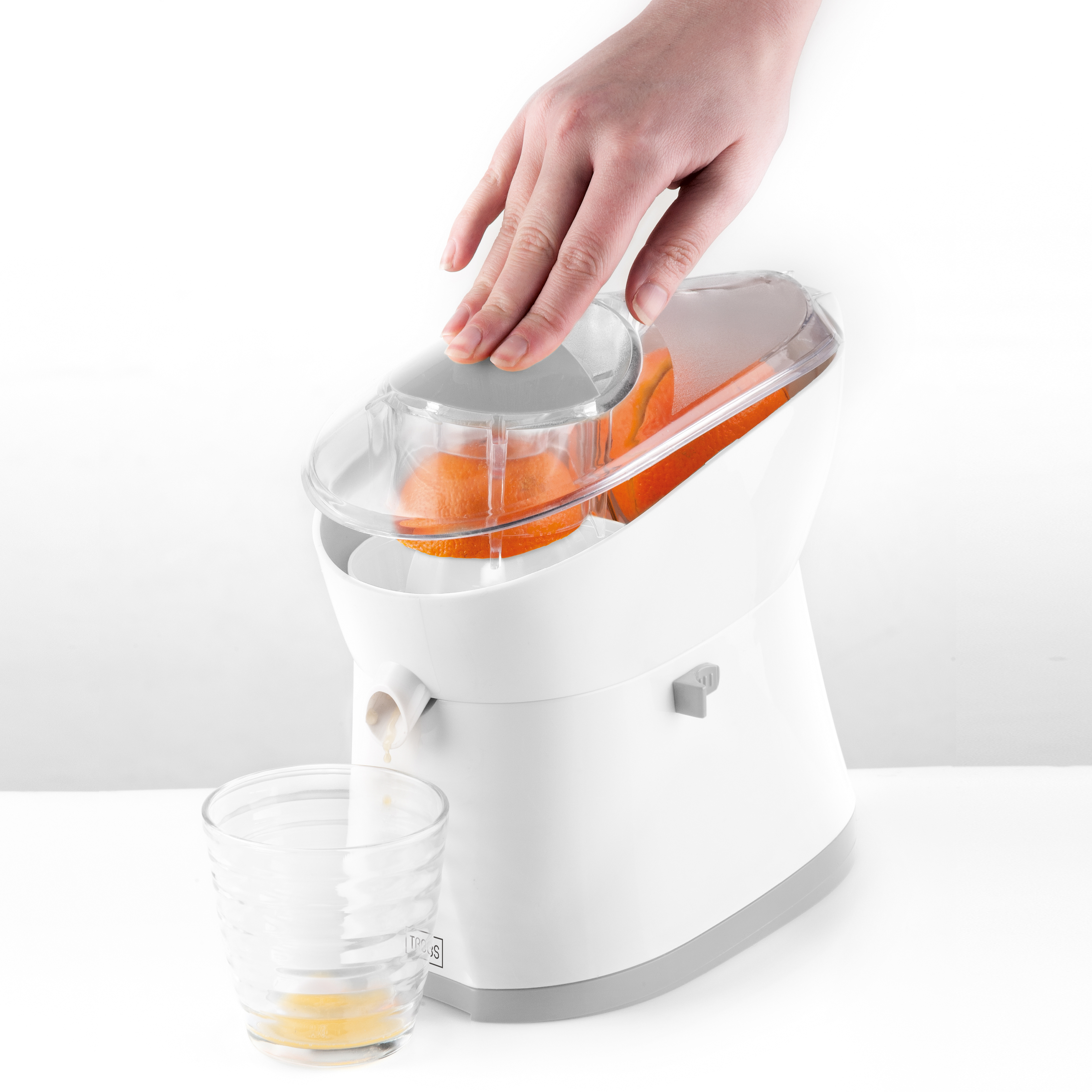 Weißer elektrischer Entsafter mit Orangenhälften, die in ein Glas gepresst werden.