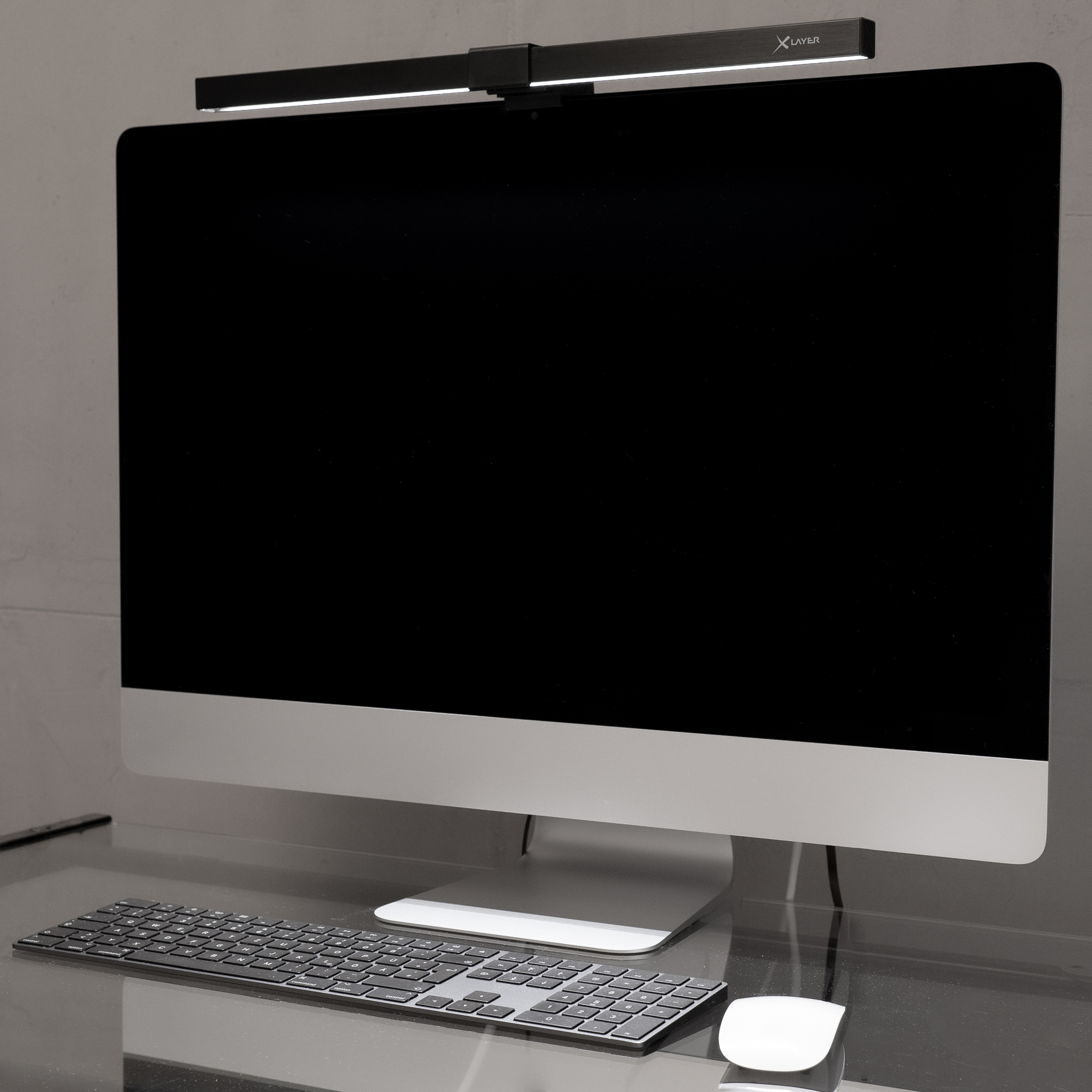 Ein Monitor mit schwarzem Bildschirm, schwarzer Lichtleiste, Tastatur und weißer Maus.