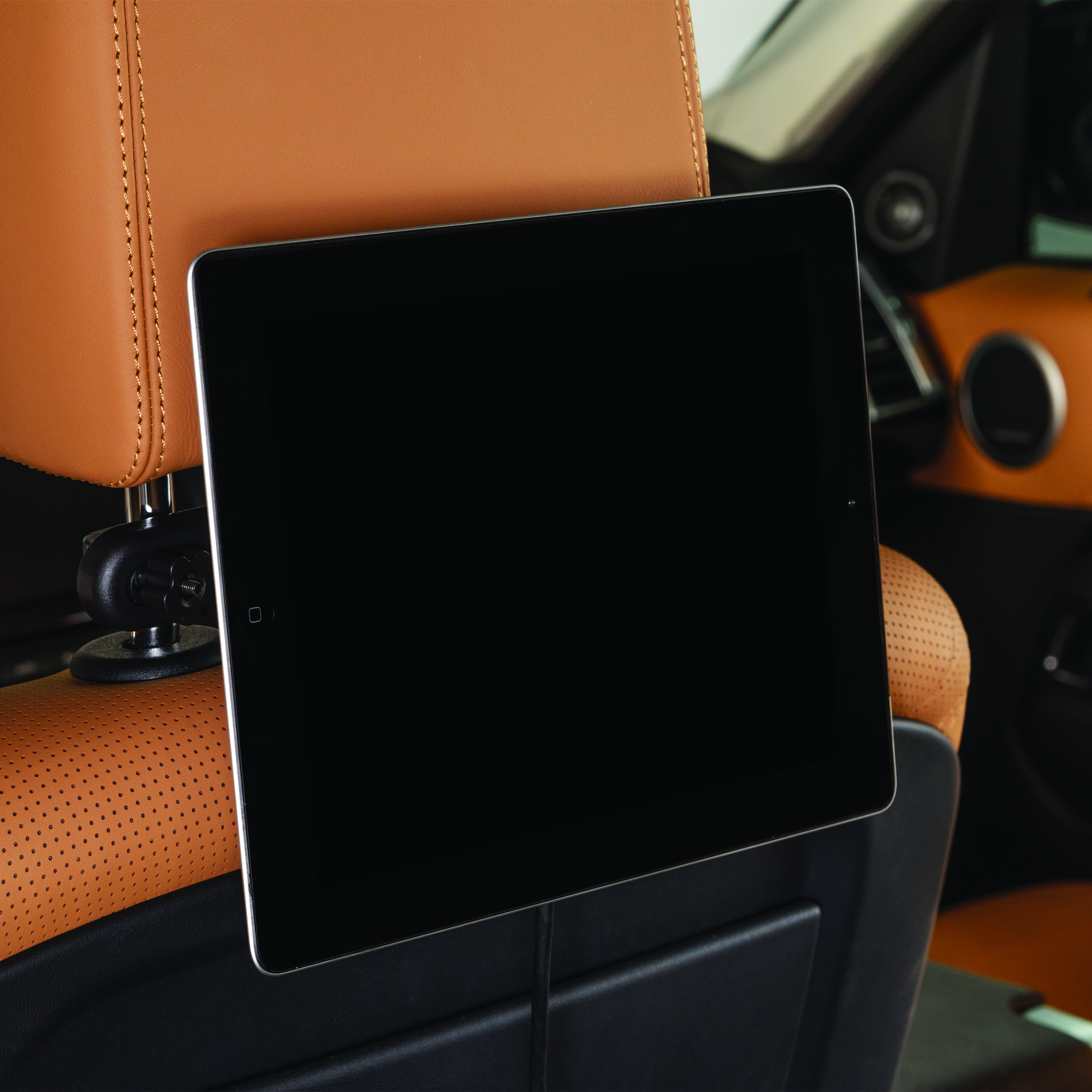 Ein Tablet, das an einer Kopfstütze im Auto befestigt ist, zum Betrachter hin abgewinkelt, mit schwarzem Bildschirm.
