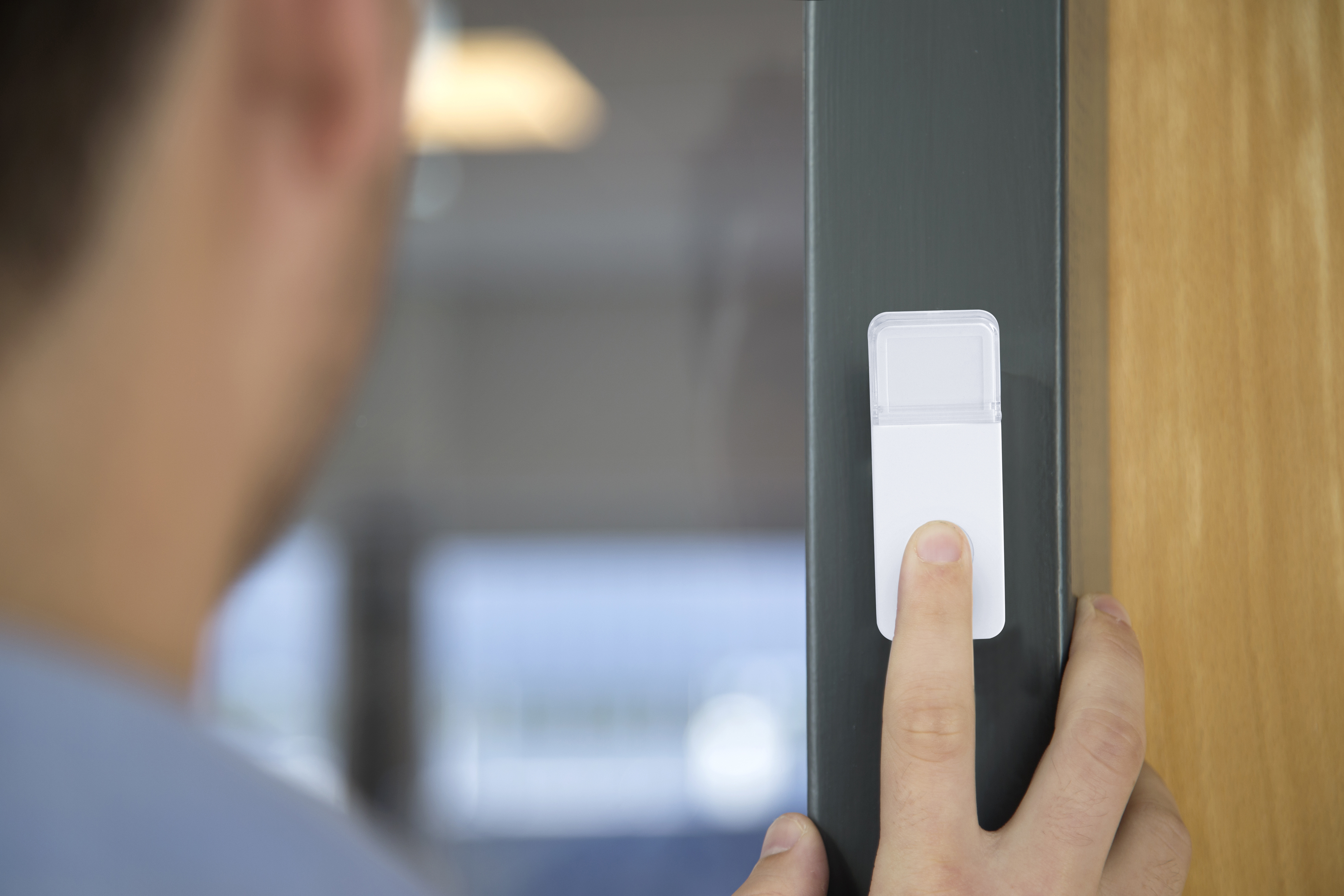 Die Hand einer Person berührt einen weißen Smart Home Türsensor.