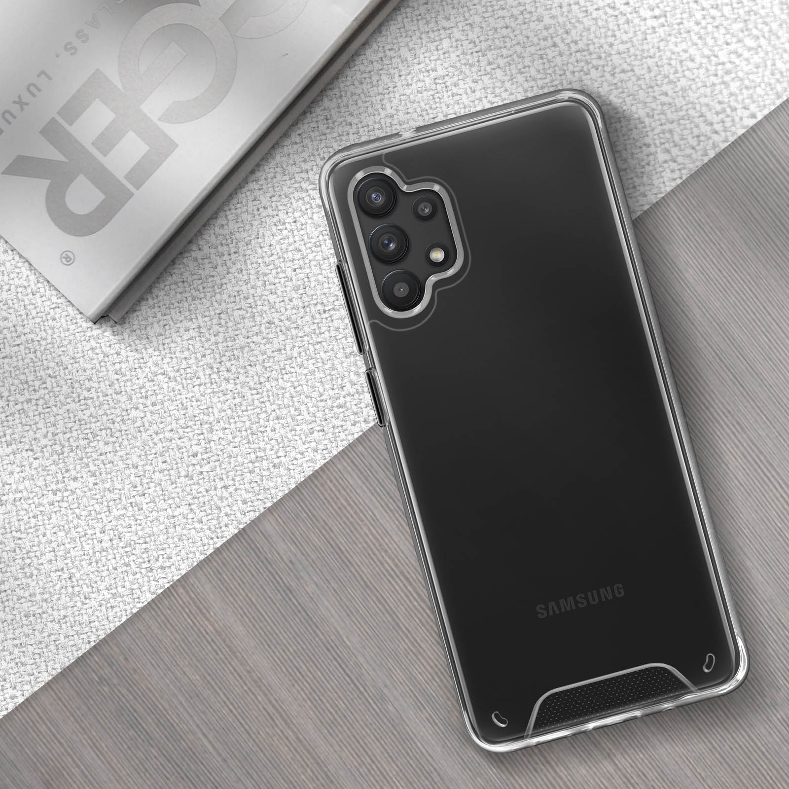 Un telefono con custodia trasparente e sistema multi-camera, su una superficie bianca e grigia.