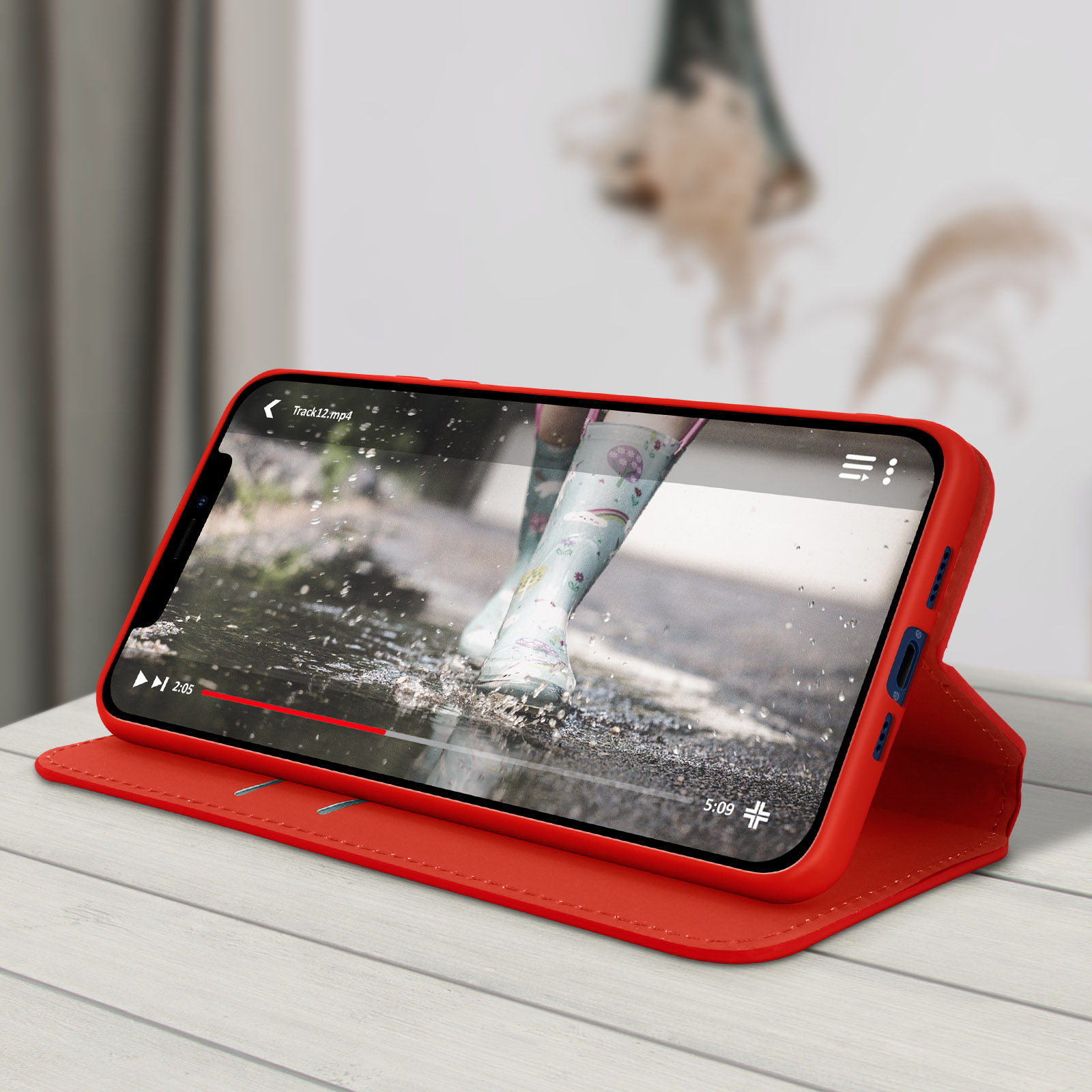 Rode telefoonhoes op een houten tafel, met videoweergave van een regenachtige scène.