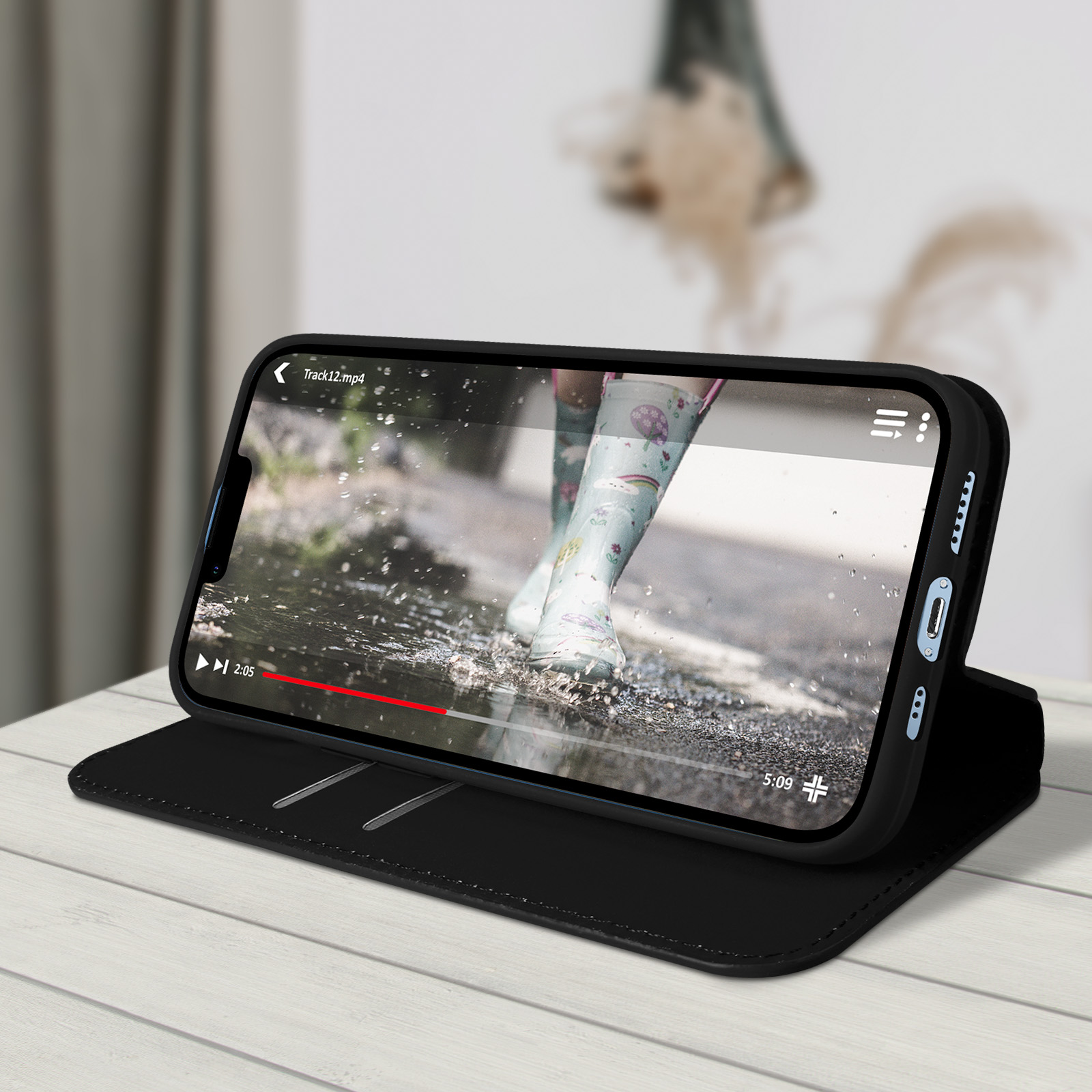 Smartphone in una custodia nera, riproduce un video, su un tavolo di legno.