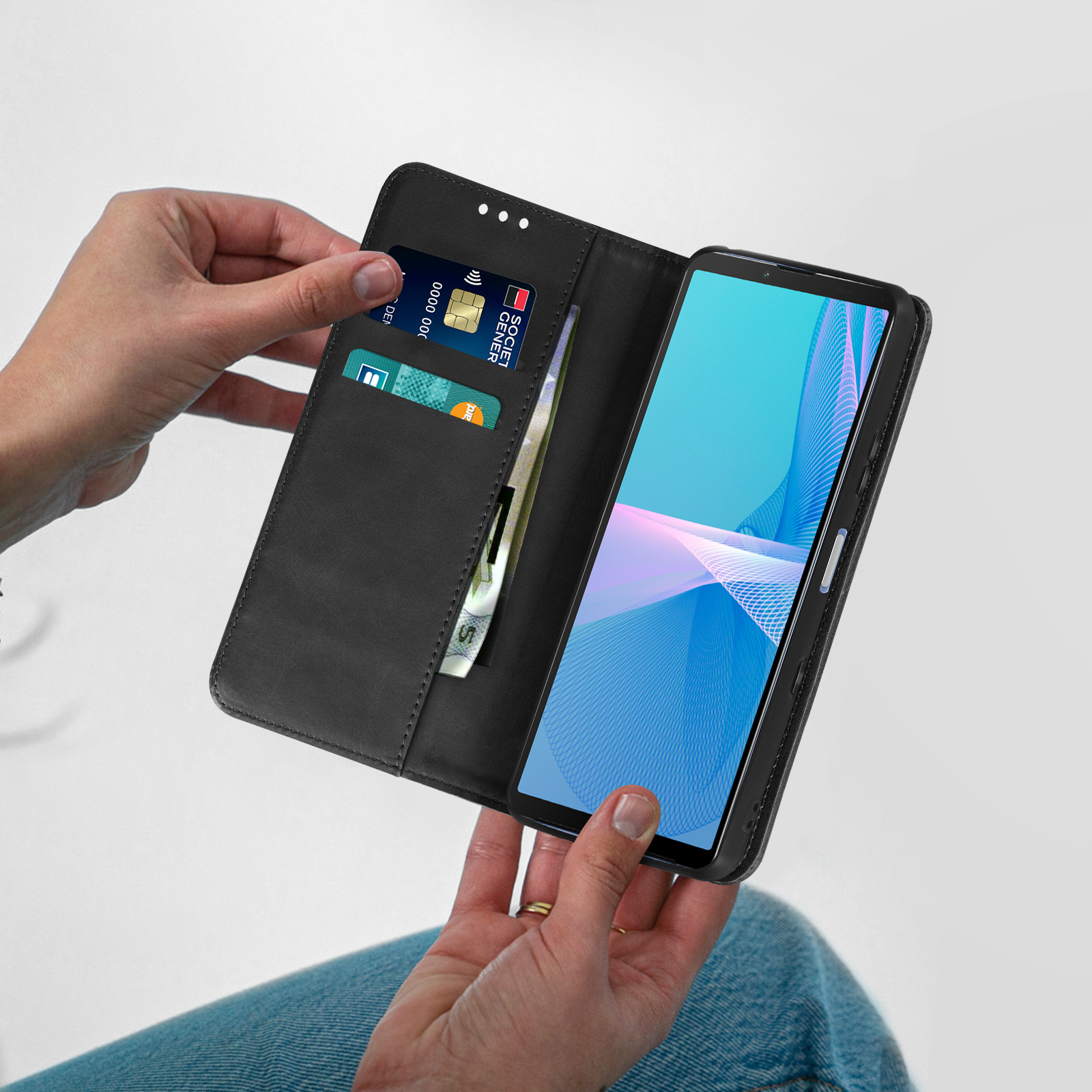 Mani che tengono una custodia nera con carte di credito e telefono all'interno.