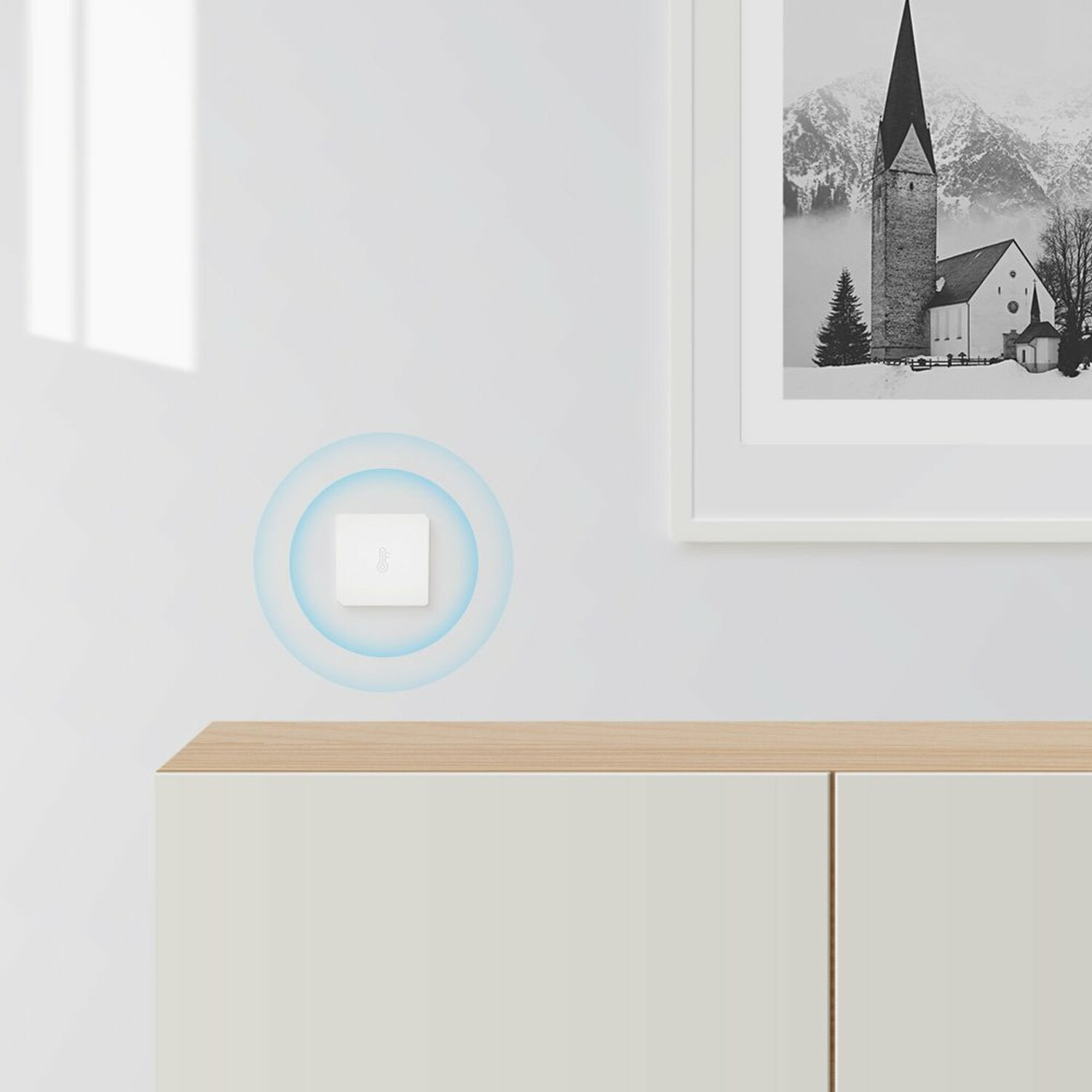 Eine weiße Wand mit einem Smart-Home-Schalter, umgeben von blauem Schein, und einem gerahmten Bild.