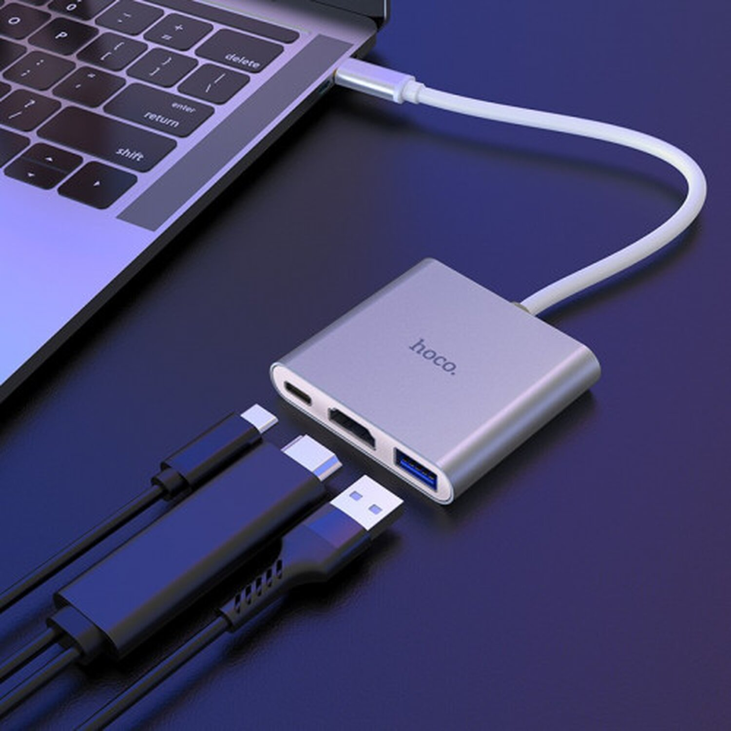 Ein silberner USB-C-Hub, der mit einem Laptop mit verschiedenen Anschlüssen verbunden ist.