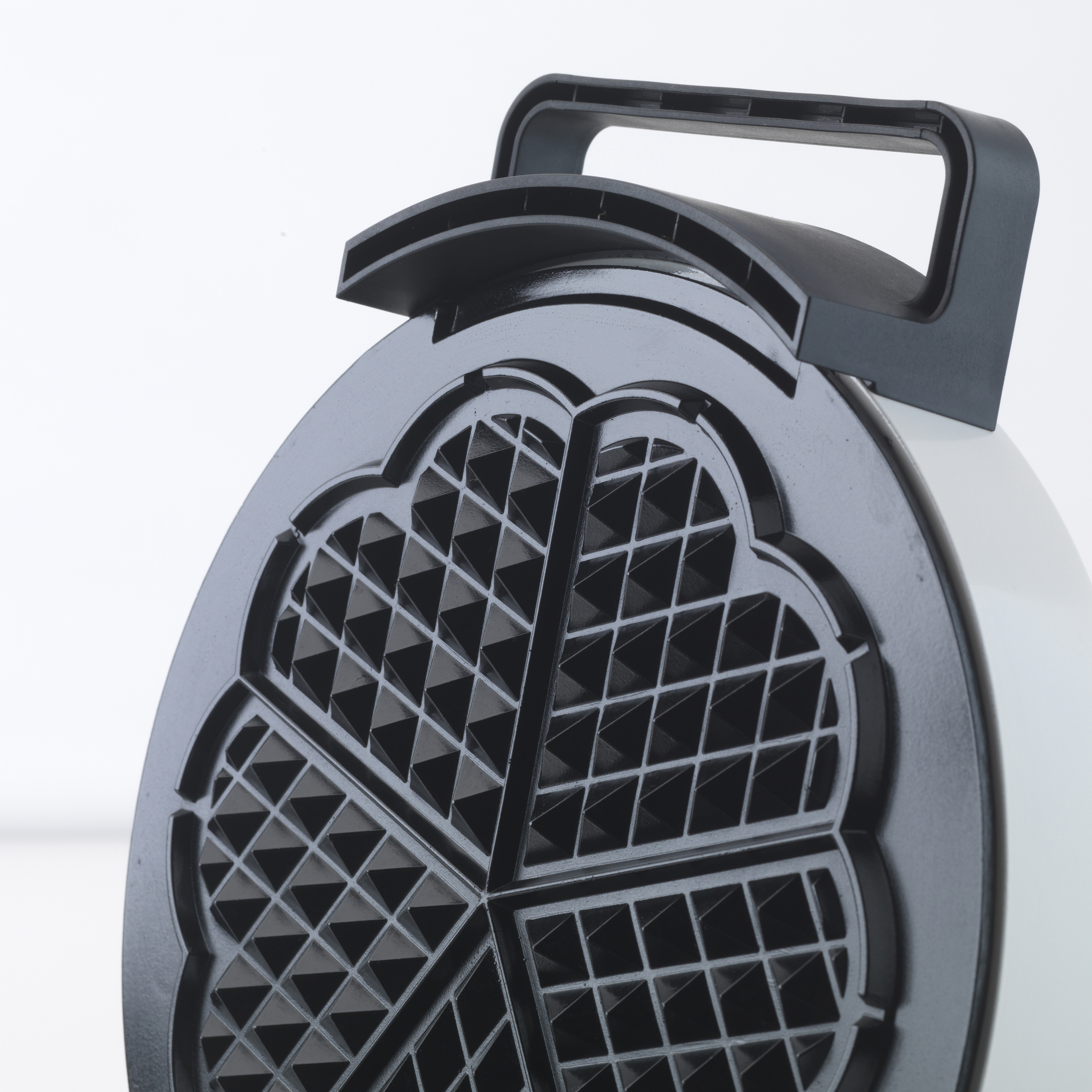 Nahaufnahme eines schwarzen Waffeleisendeckels mit Griff. Es hat ein gitterartiges Design zur Herstellung von Waffeln.