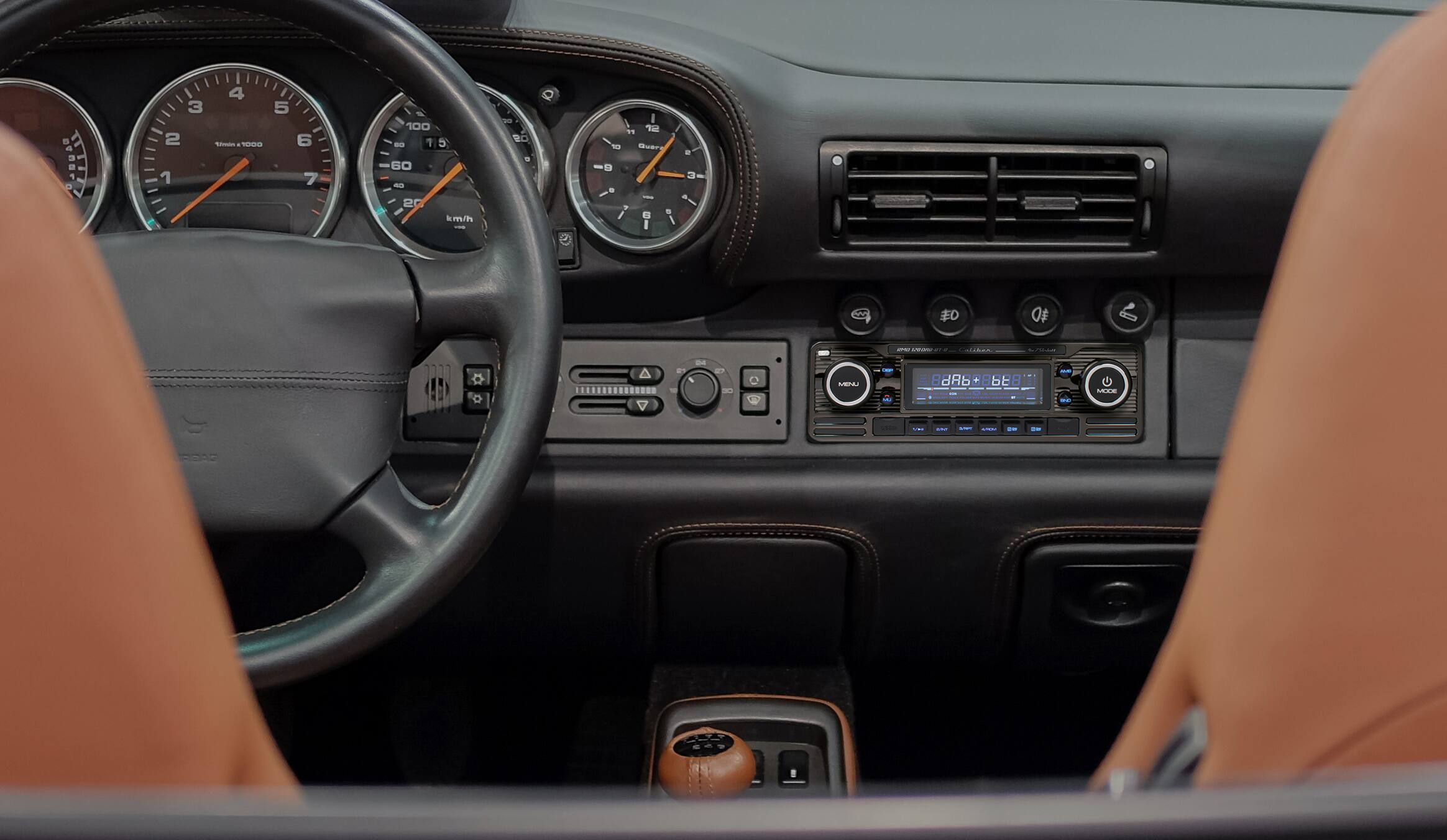Interior view of a classic car dashboard, showing gauges, steering wheel, and radio.