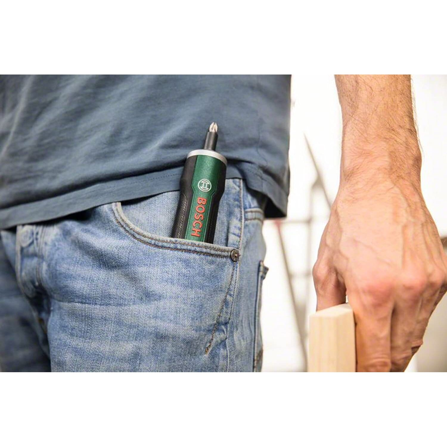 Zielono-czarna wkrętarka akumulatorowa w kieszeni dżinsów z drewnianym klockiem.