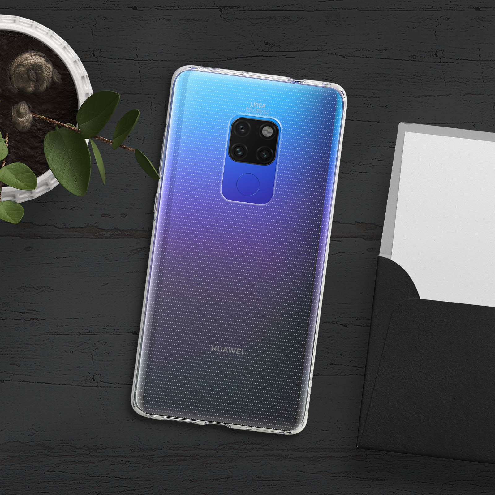 Smartphone mit Hülle auf Holztisch mit Pflanze und Umschlag.