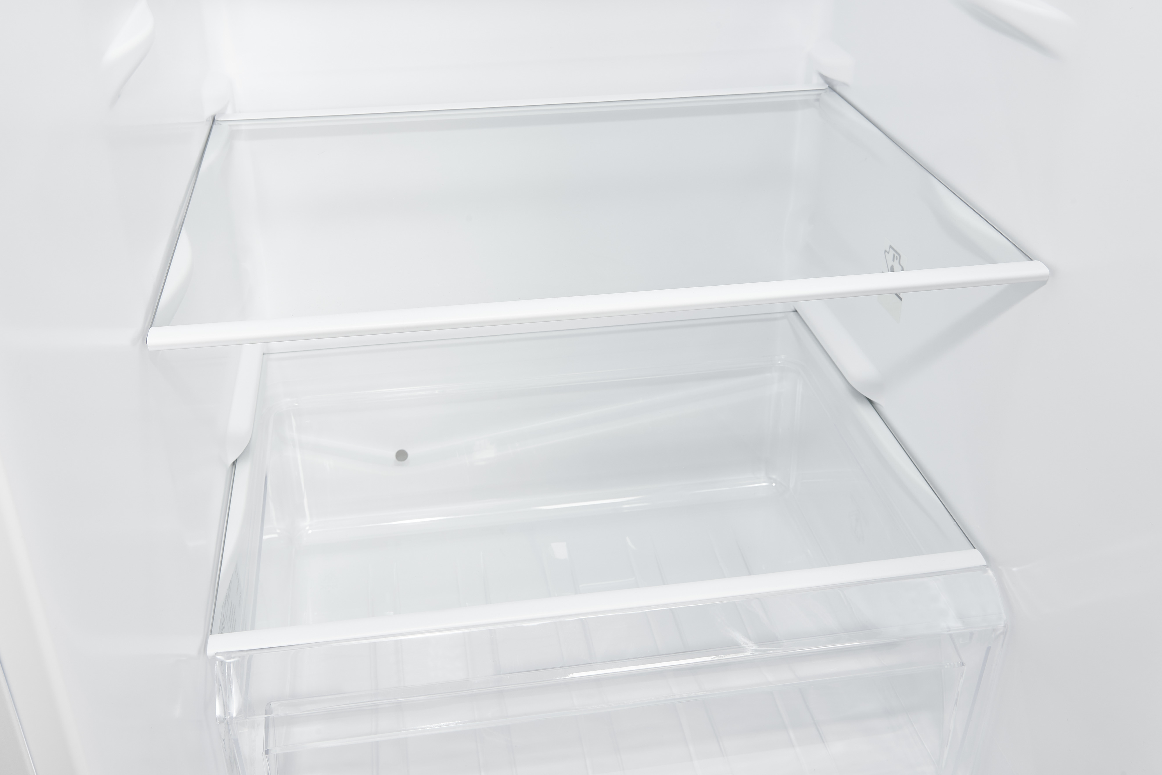 Ein leerer Kühlschrank mit Glasablagen und einer Schublade.