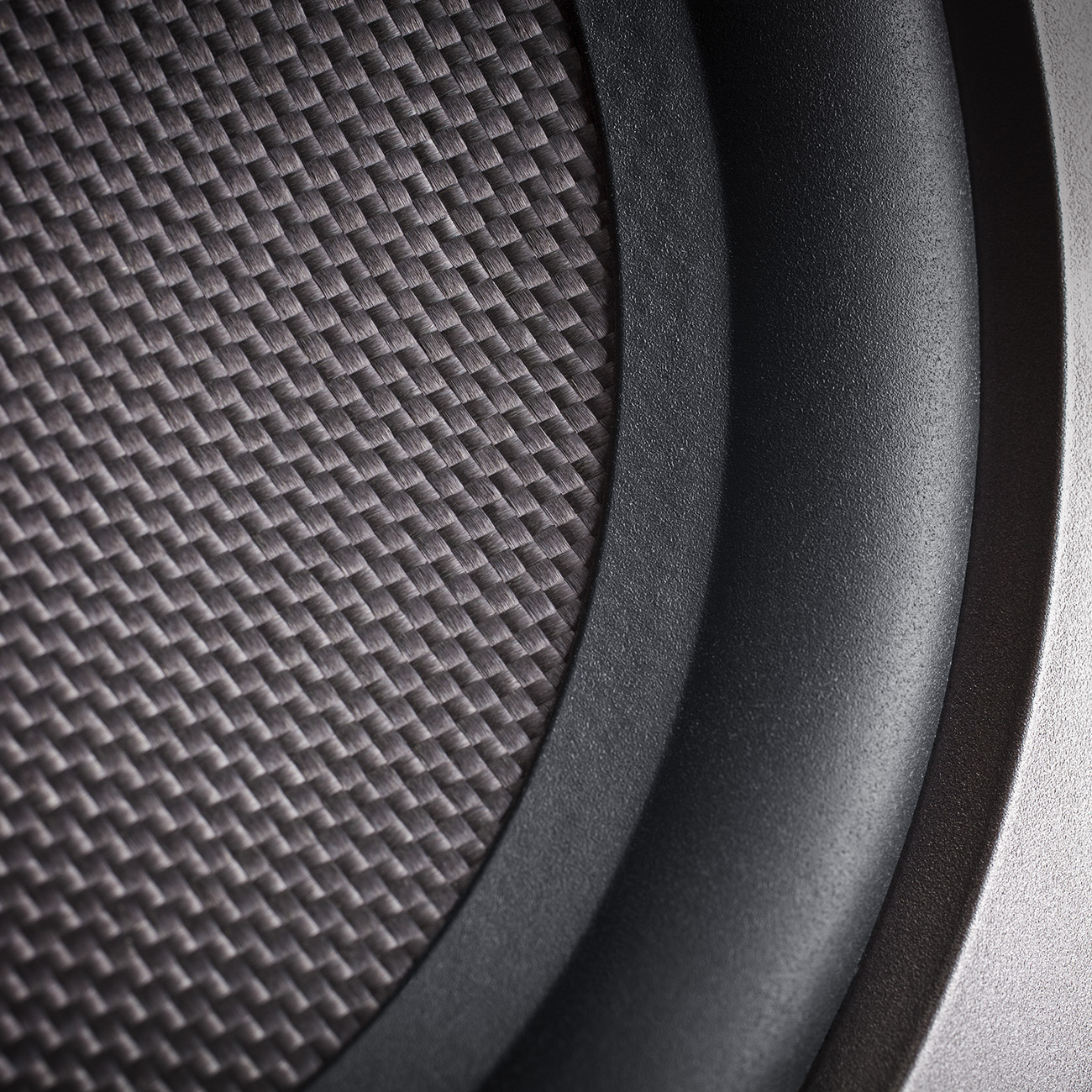 Nahaufnahme eines Subwoofer-Lautsprecherkegels mit strukturierter Oberfläche, umgeben von einem schwarzen Gummiring.