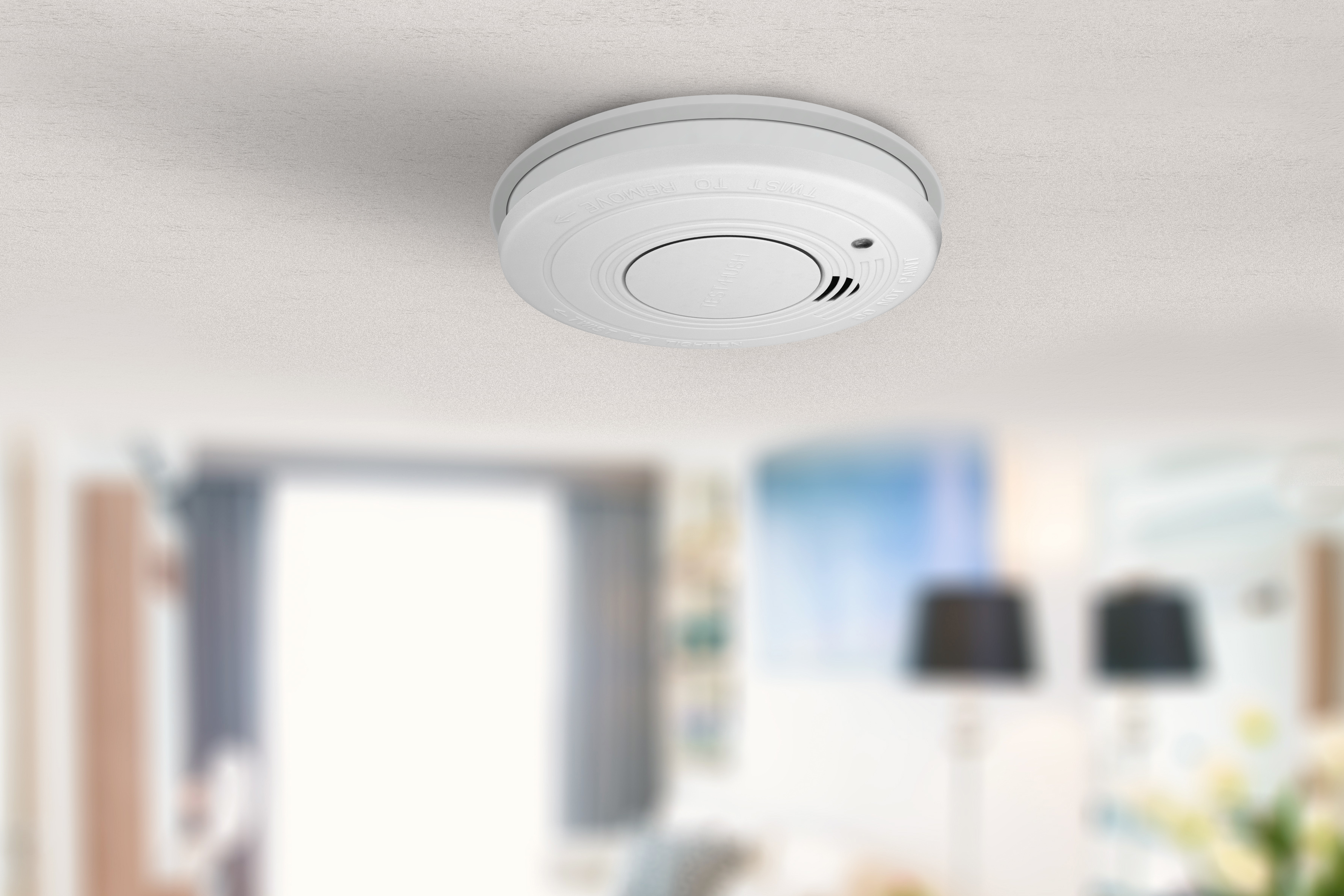 Czujnik dymu na białym suficie, rozmyte wnętrze.