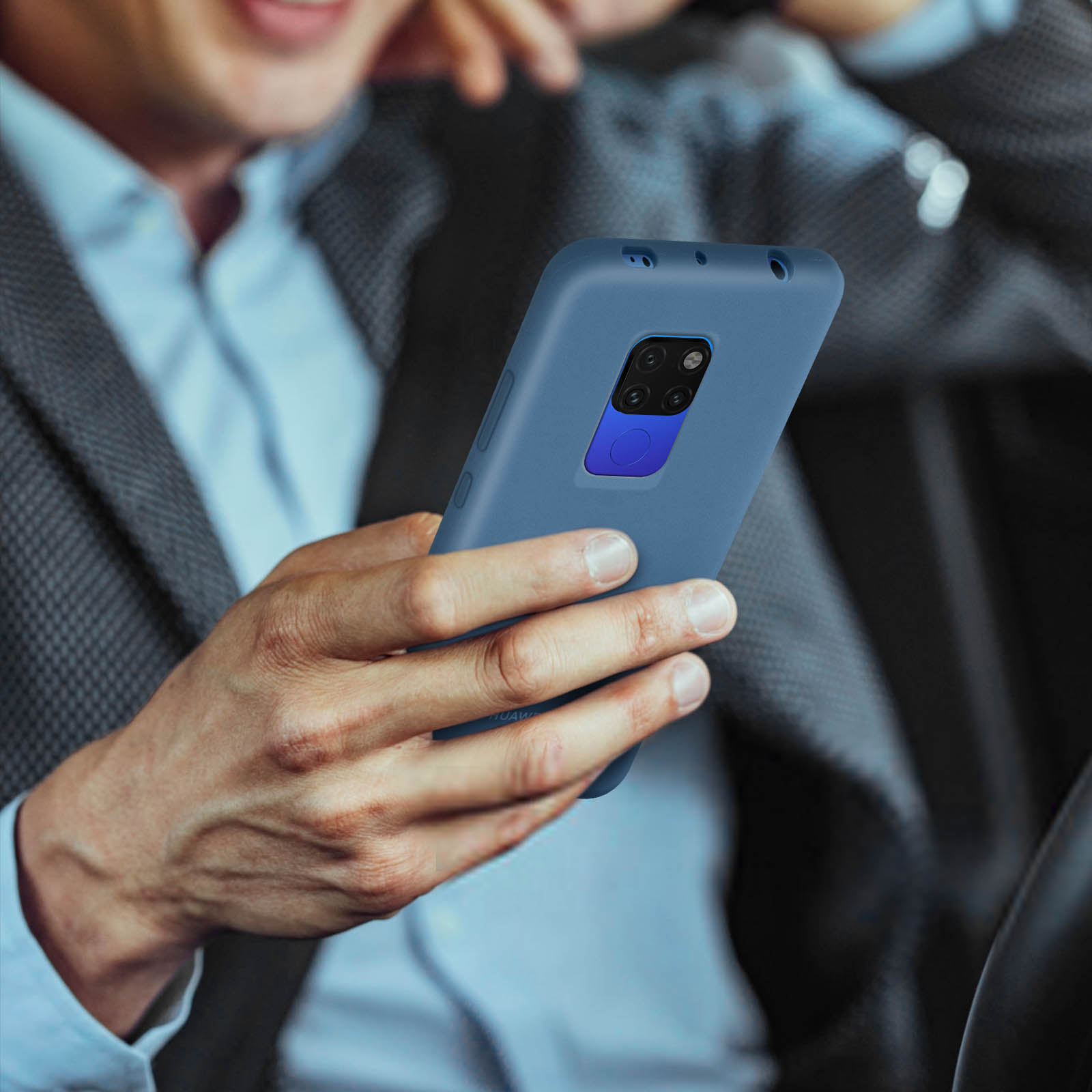 Una persona sosteniendo un teléfono azul, con un fondo borroso. La persona está en un coche.