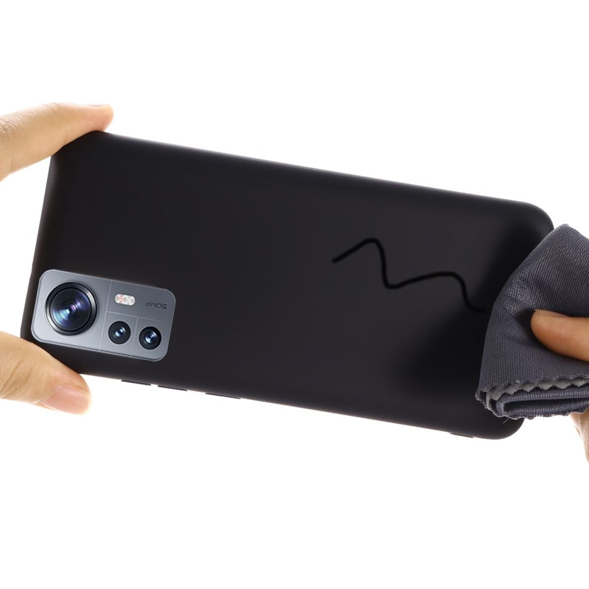 Eine Hand hält ein schwarzes Smartphone mit Dreifachkamera und einem Putztuch.