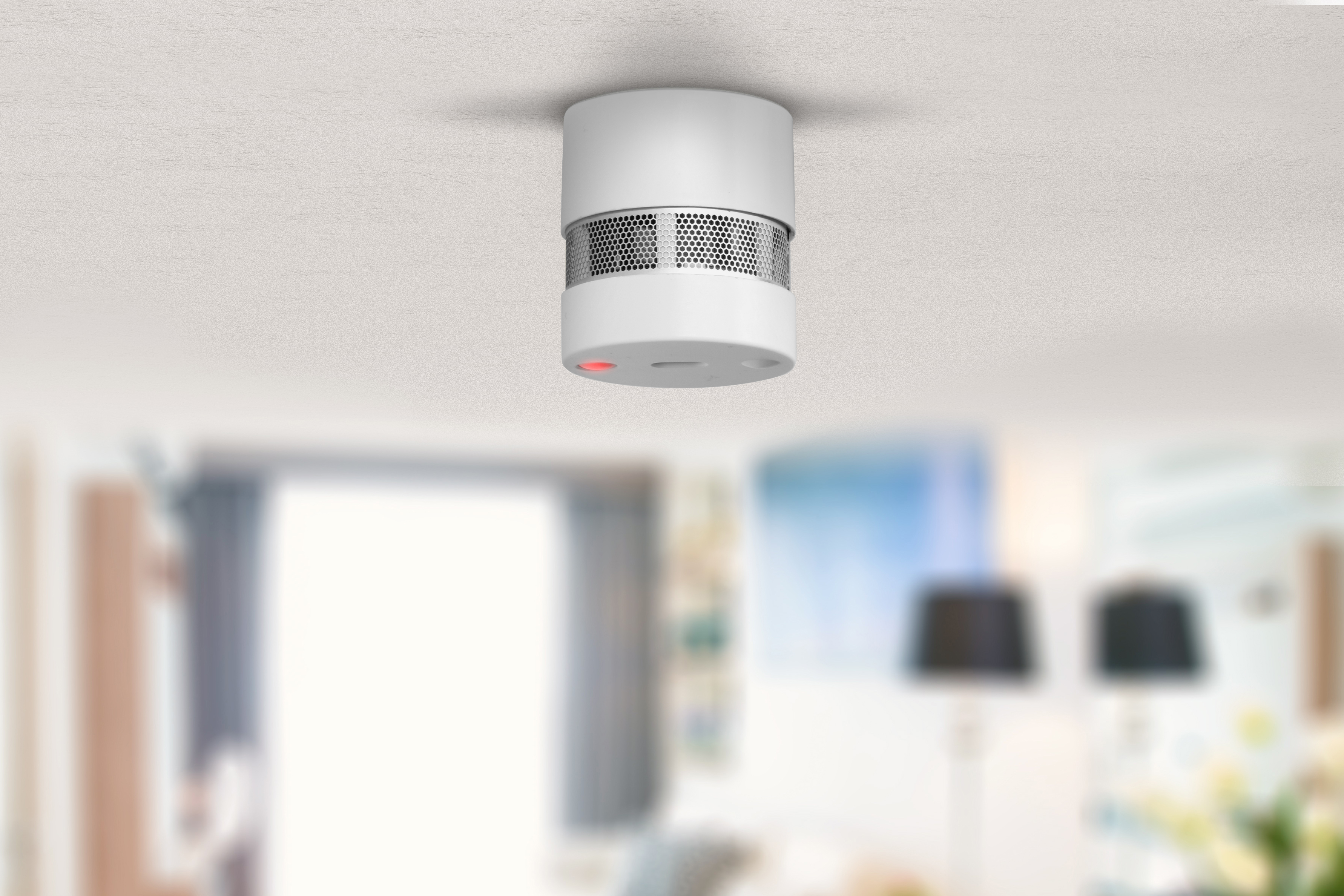 Détecteur de fumée au plafond blanc, vue aérienne, dans un cadre de pièce.