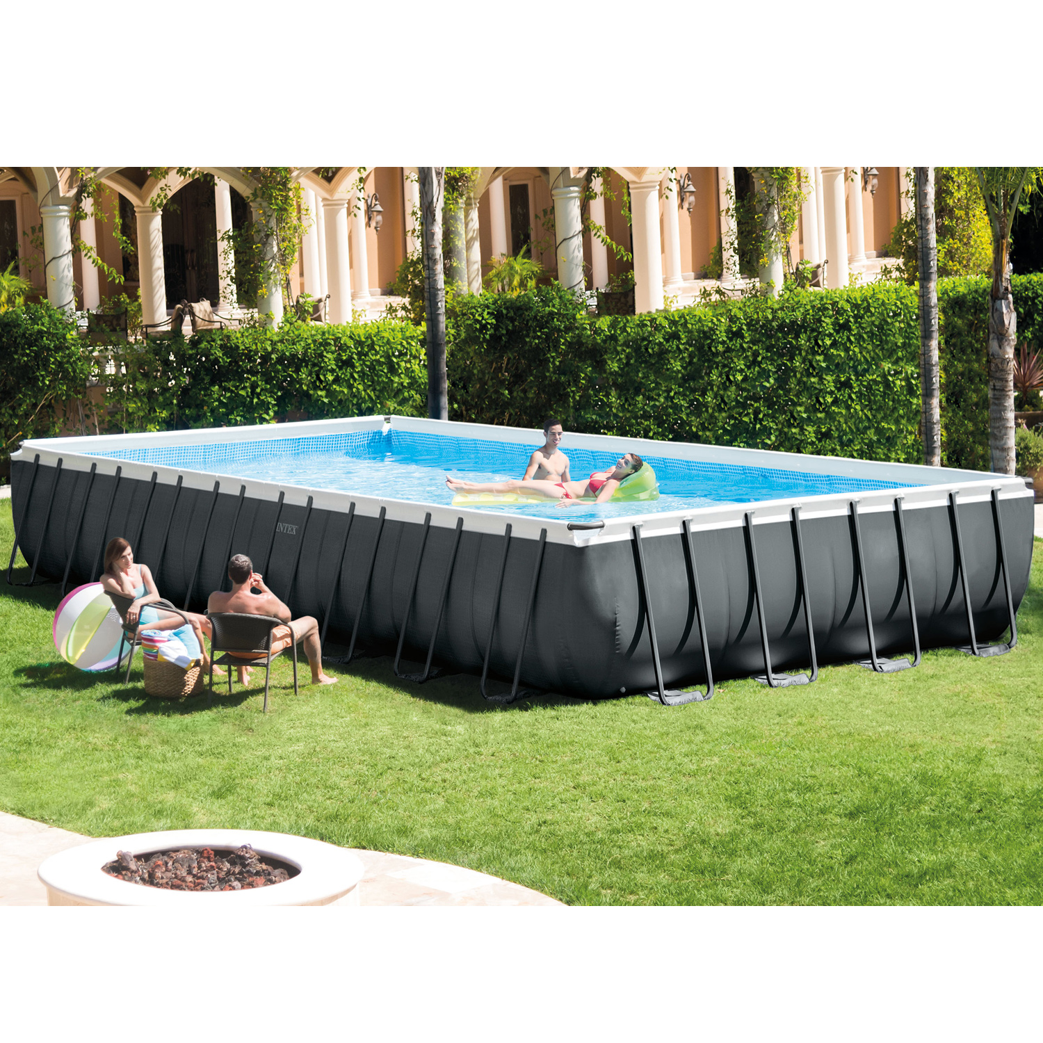 Ein großer rechteckiger Pool mit Personen drinnen und draußen. Der Pool befindet sich in einem grasbewachsenen Garten.