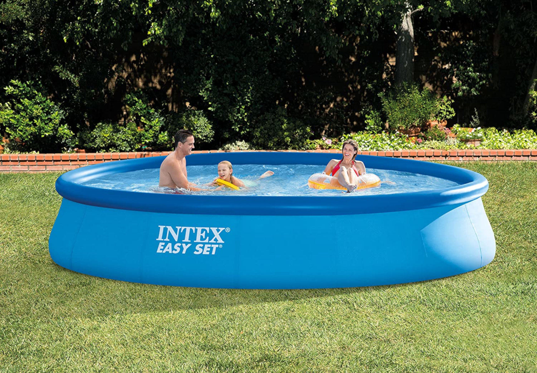 Leute in einem blauen aufblasbaren Pool in einem grasbewachsenen Garten. Der Pool hat den Text "Intex Easy Set".