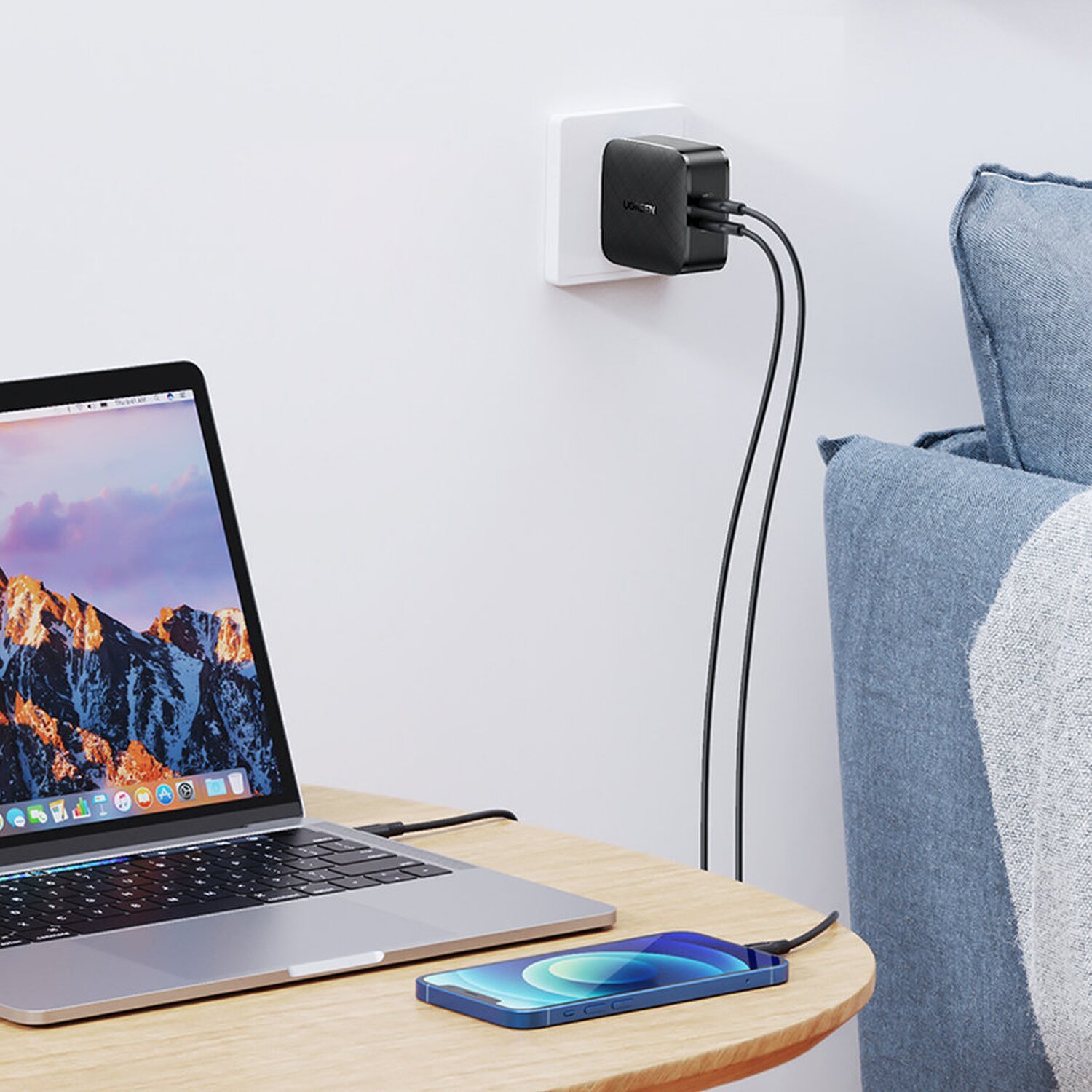 Ein UGREEN Wandladegerät mit zwei Anschlüssen, das einen Laptop und ein Telefon lädt.