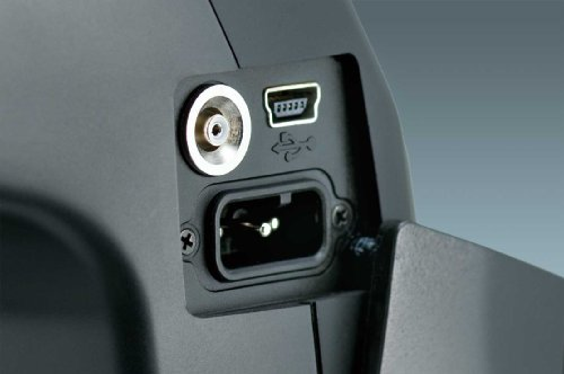Primer plano de un dispositivo negro con puertos. Incluye tomas USB y cable de alimentación.