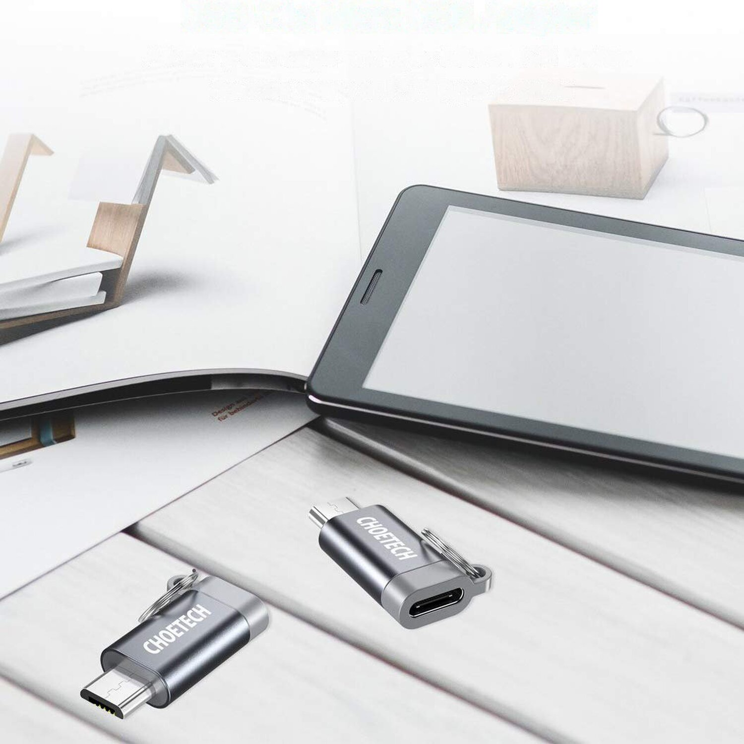 Ein Tablet und zwei USB-C-Adapter liegen auf einem Schreibtisch. Das Tablet ist im Hintergrund.