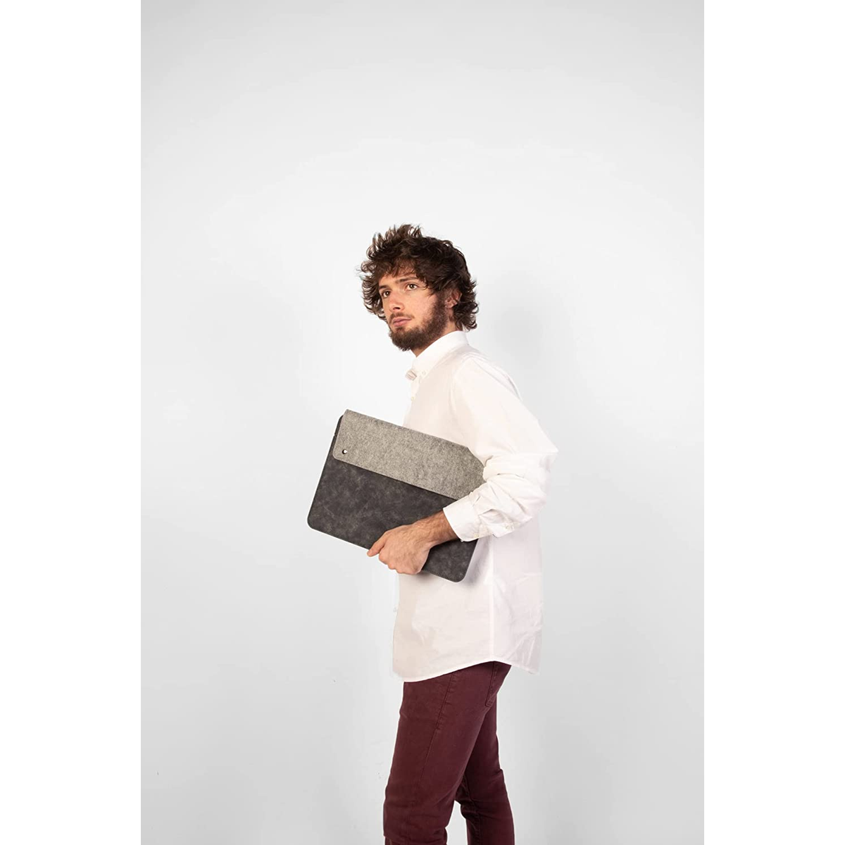 Uomo con camicia bianca e pantaloni bordeaux che tiene una custodia grigia e nera.