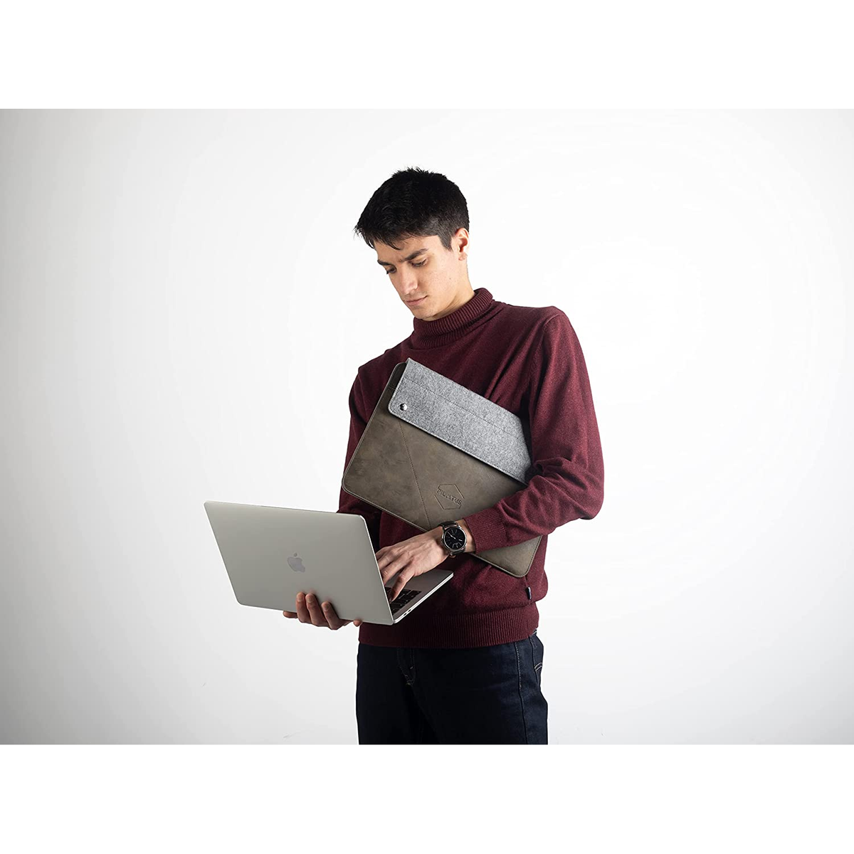 Un uomo che tiene un laptop e una custodia, focalizzato sul laptop, su sfondo bianco.