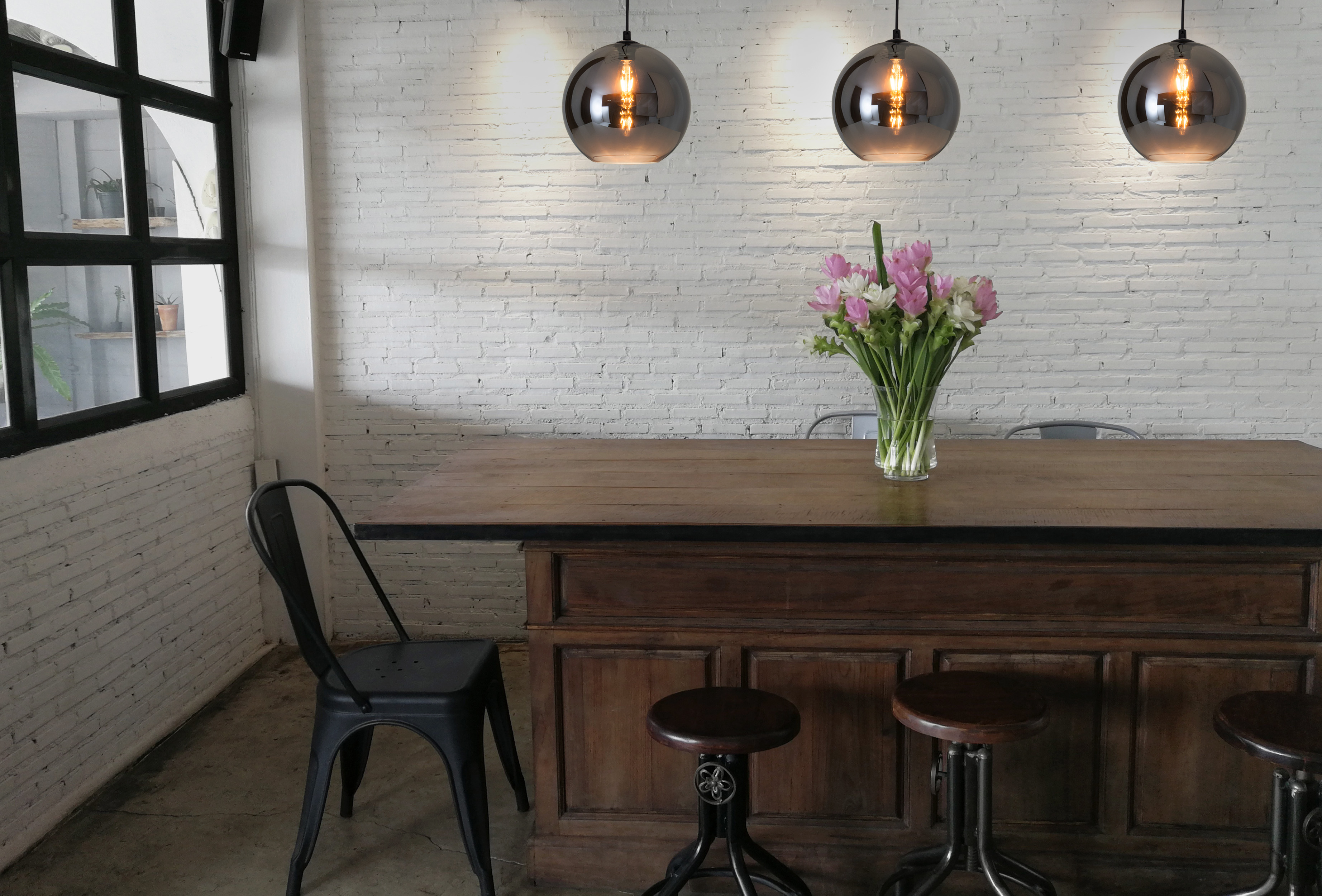 Prise de vue intérieure d'un coin repas avec une table en bois et des suspensions.