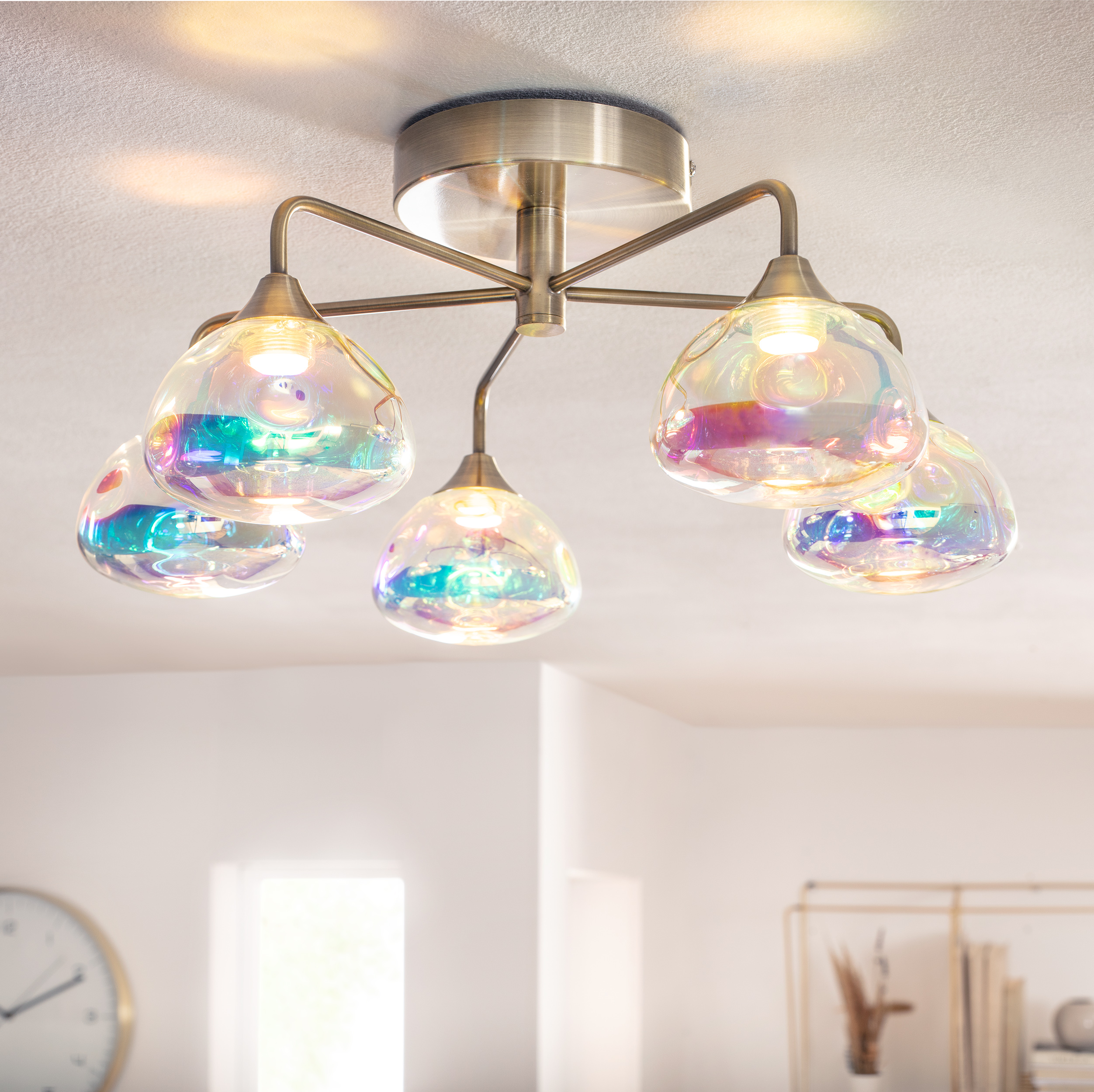 Deckenleuchte mit mehreren irisierenden Glasschirmen. Leuchte an einer weißen Decke.