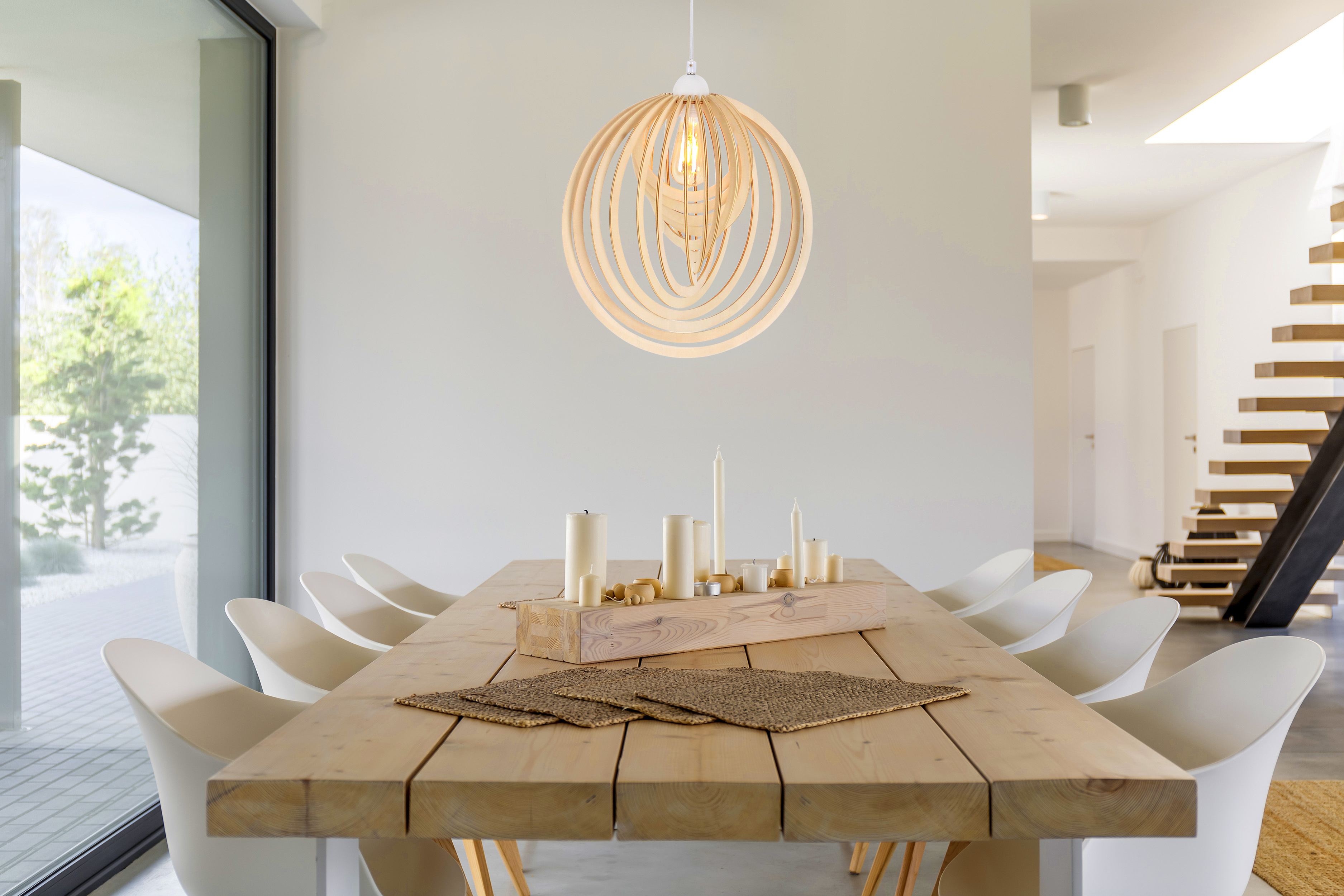 Holz-Kronleuchter mit Glühbirne über einem Holztisch mit Kerzen und Dekorationen.