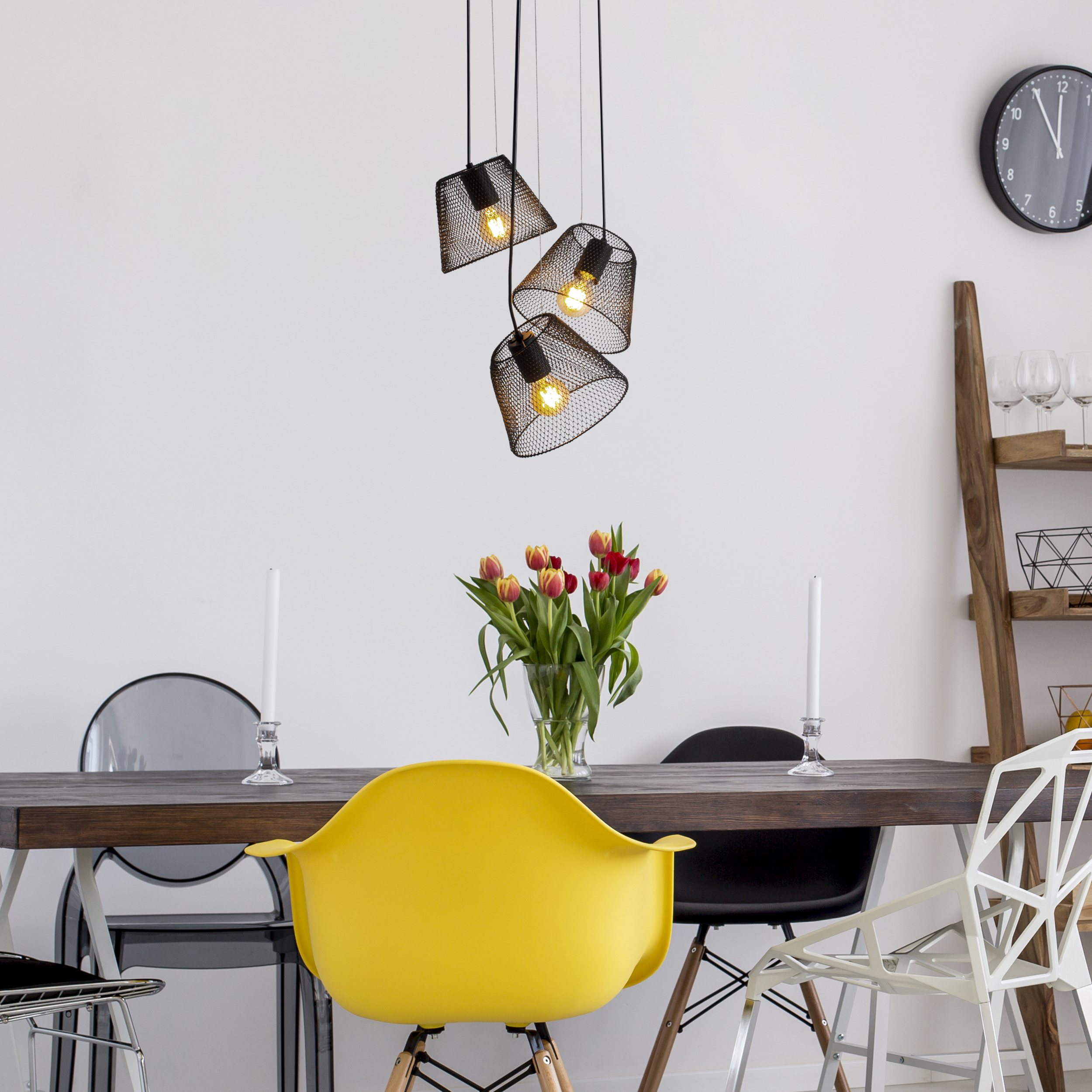 Esszimmer mit dunklem Tisch, gelbem Stuhl und Blumenvase mit Hängelampen.