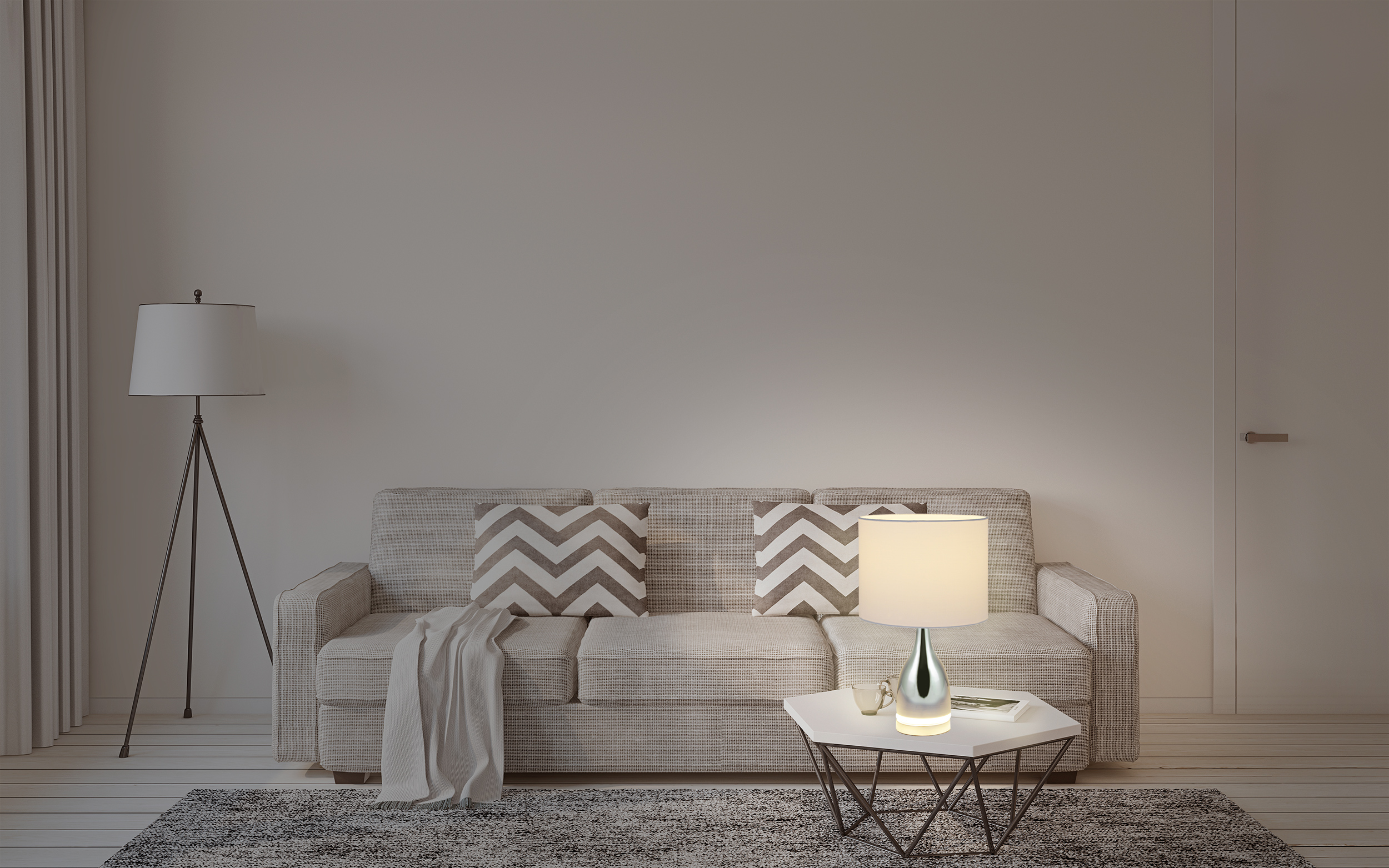 Wohnzimmer mit Sofa, Kissen, Beistelltisch mit Lampe und Teppich. Der Raum ist schwach beleuchtet.