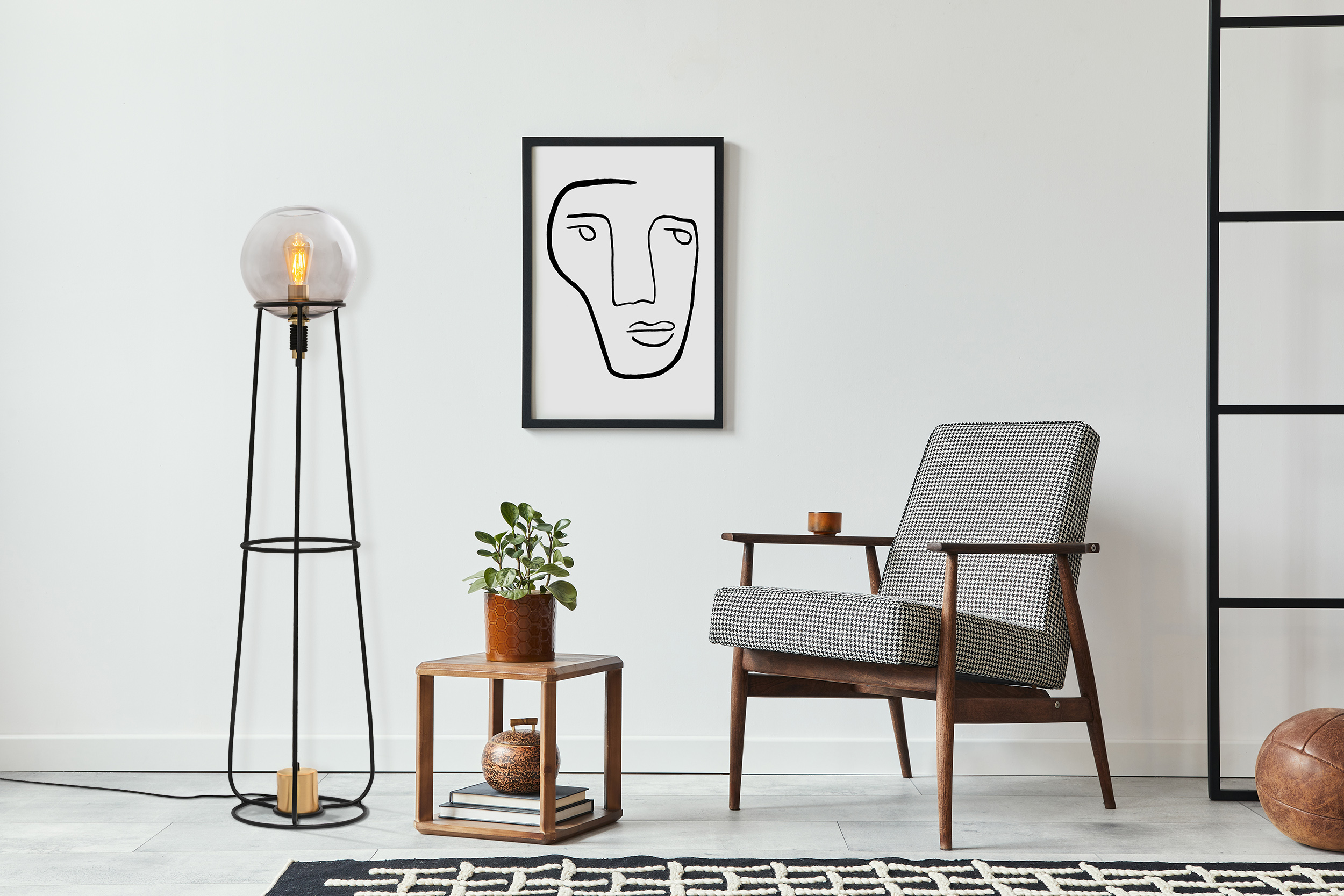 Innenraum mit moderner Lampe, Kunstwerk, Sessel und Beistelltisch mit Pflanze.